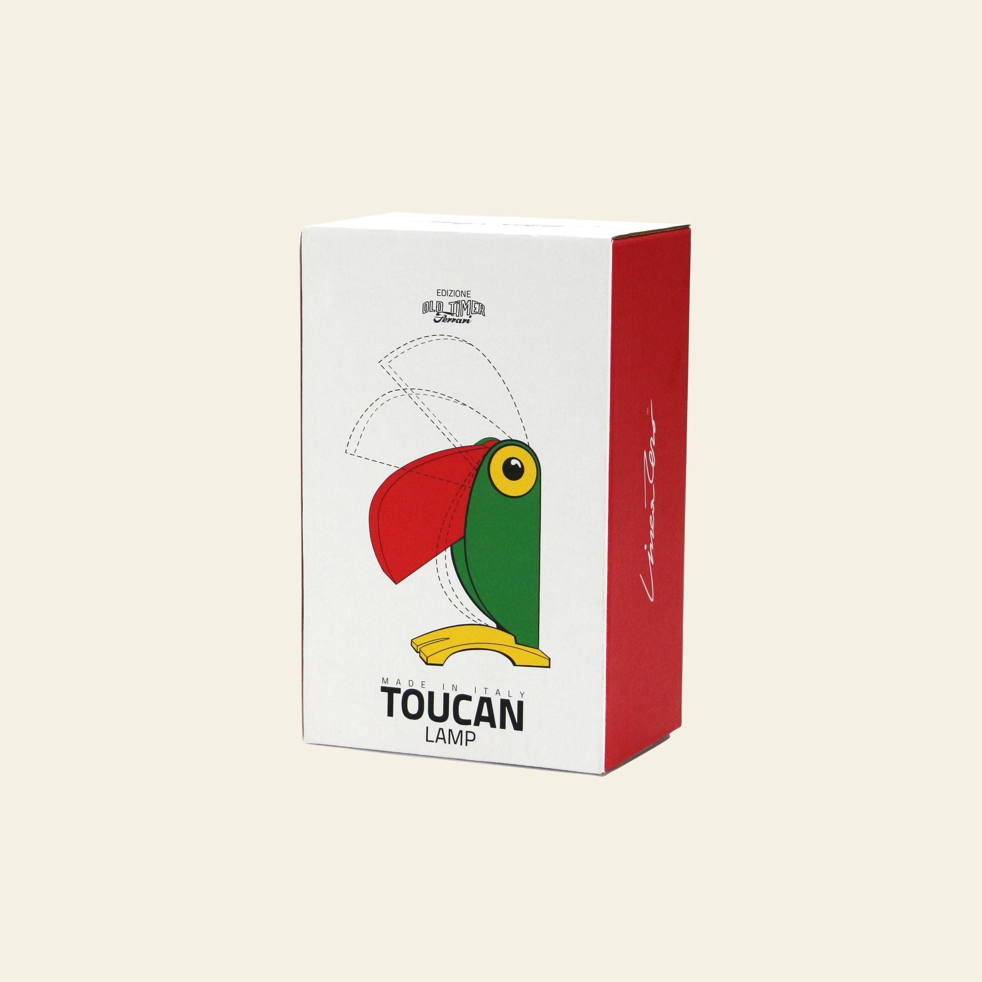 A rectangular product box for the DETAIL Toucan Lamp by DETAIL highlights its colorful toucan-shaped design—green body, yellow beak, red head—set against a cream background with bold red side panels for vintage appeal.