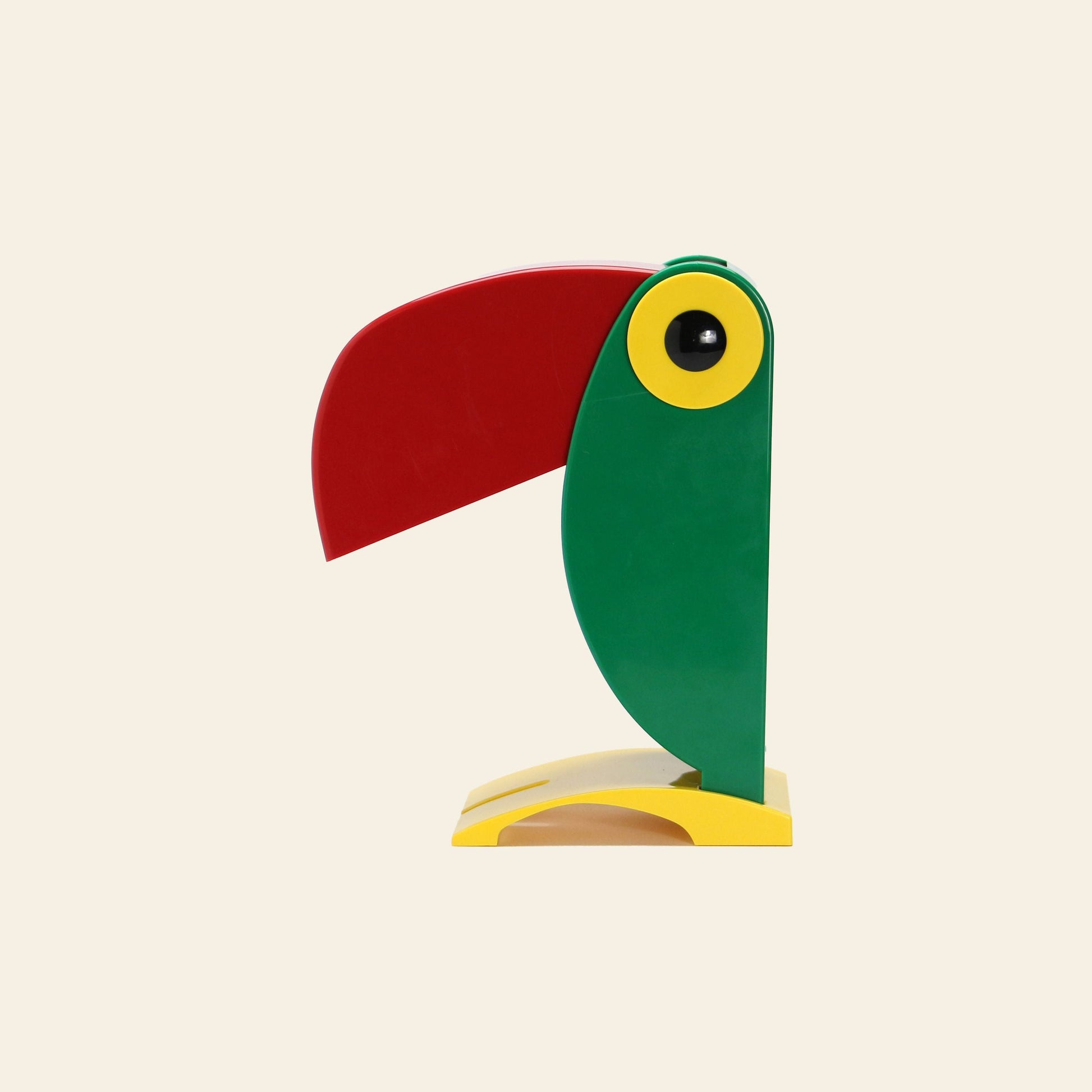 The DETAIL Toucan Lamp by DETAIL is a minimalist, vintage-inspired lamp shaped like a toucan in green, yellow, red, and black geometric forms, shown in profile against a plain light background.