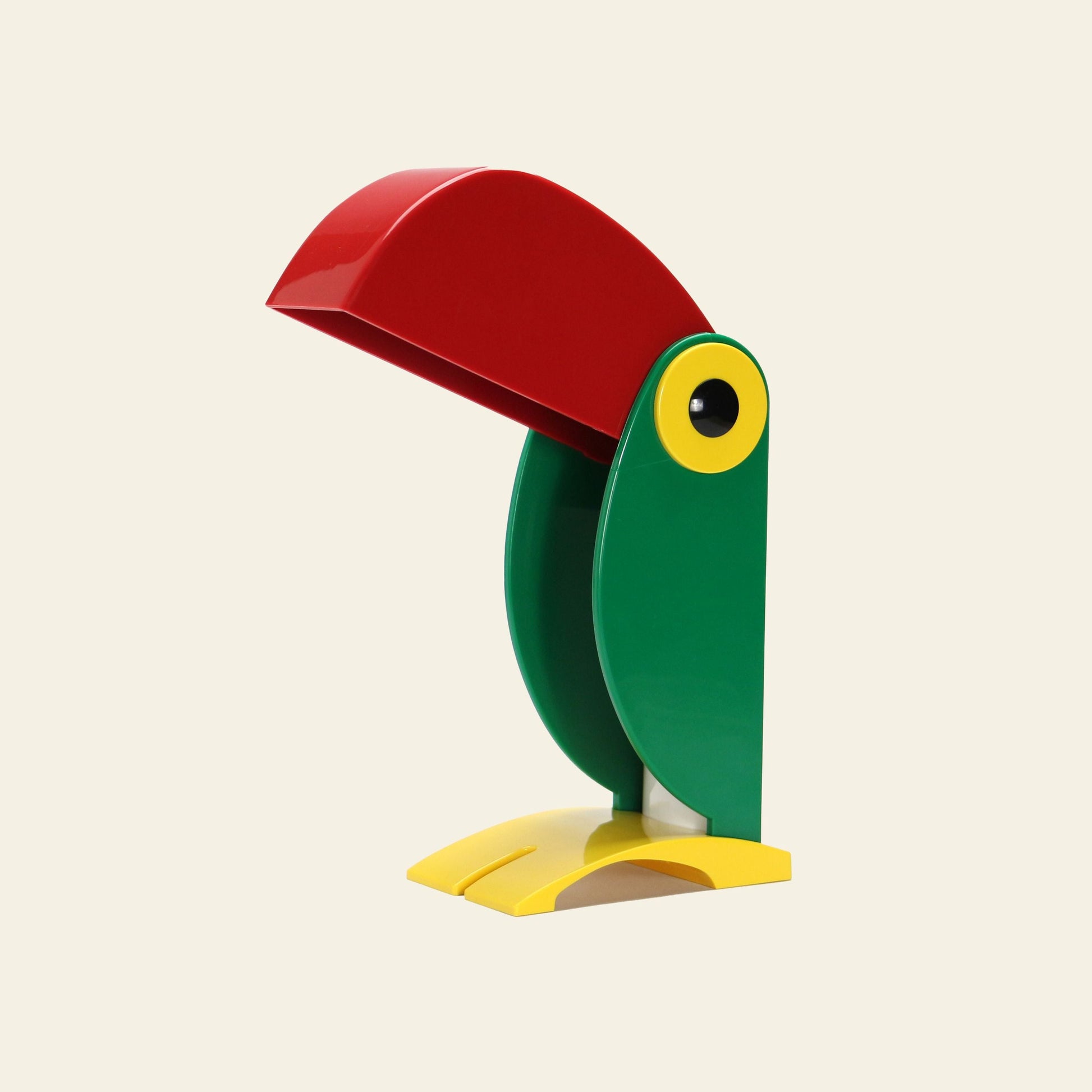 The DETAIL Toucan Lamp by DETAIL features a red beak, green body, and yellow feet, adding vintage charm to your space against a plain light background.