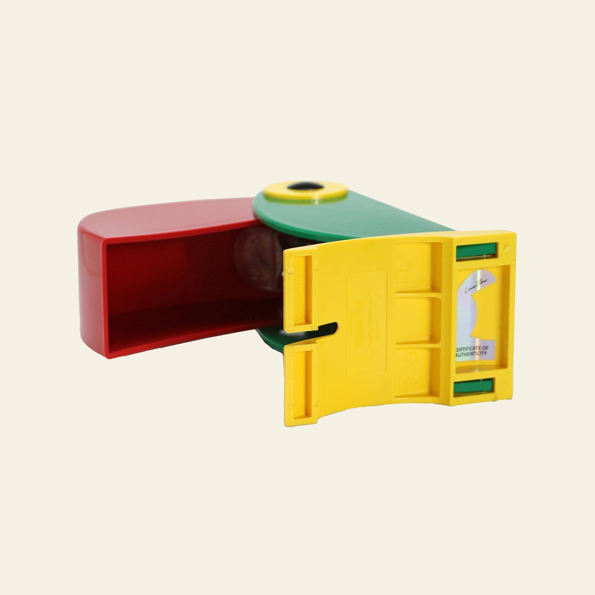 The DETAIL Toucan Lamp by DETAIL features vintage charm with red, green, and yellow plastic parts, a circular top hole, and a yellow compartment with printed instructions, all set against a plain beige background.