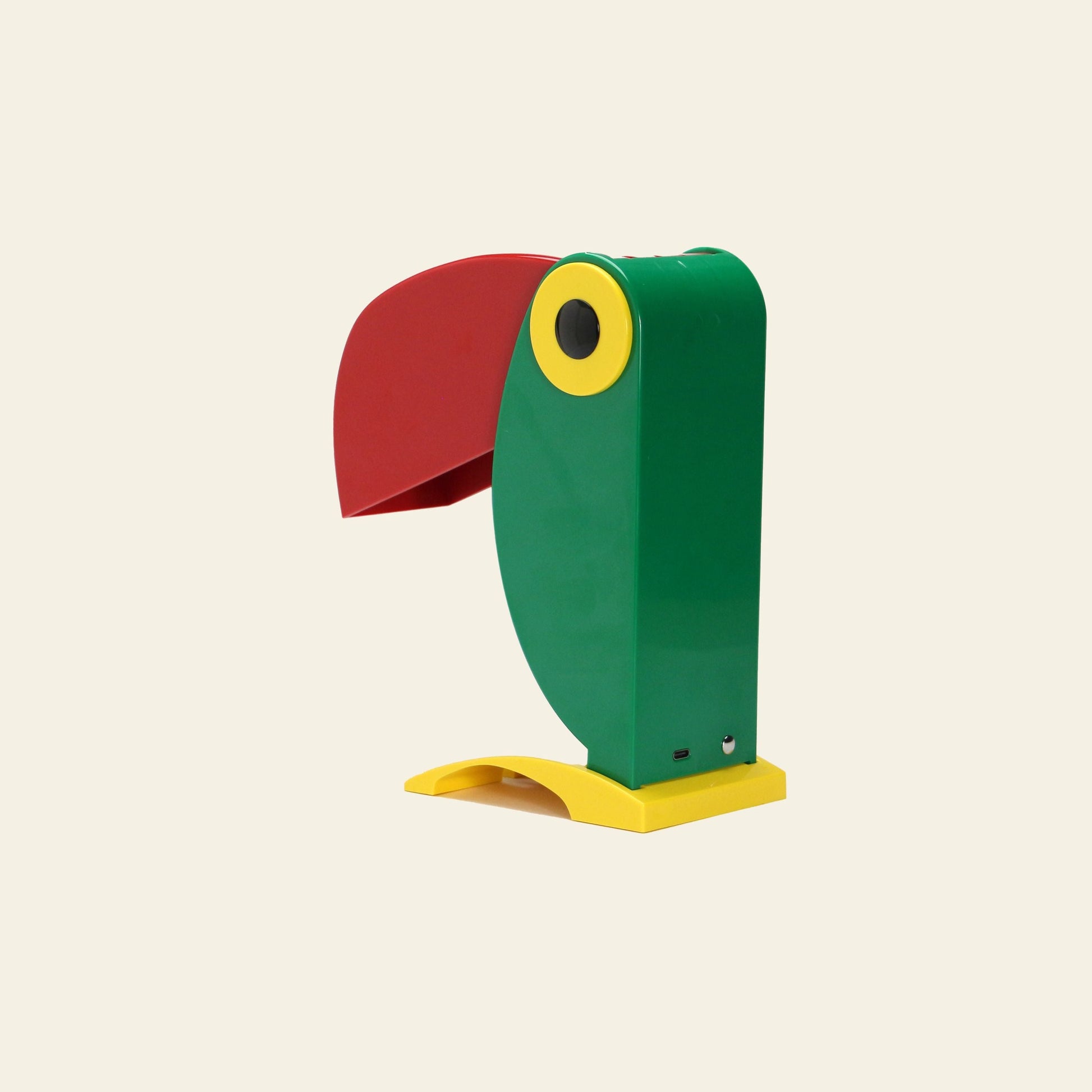 The DETAIL Toucan Lamp by DETAIL features a playful, vintage-inspired design with a green body, red beak, and yellow accents—an iconic piece set against a simple light background.