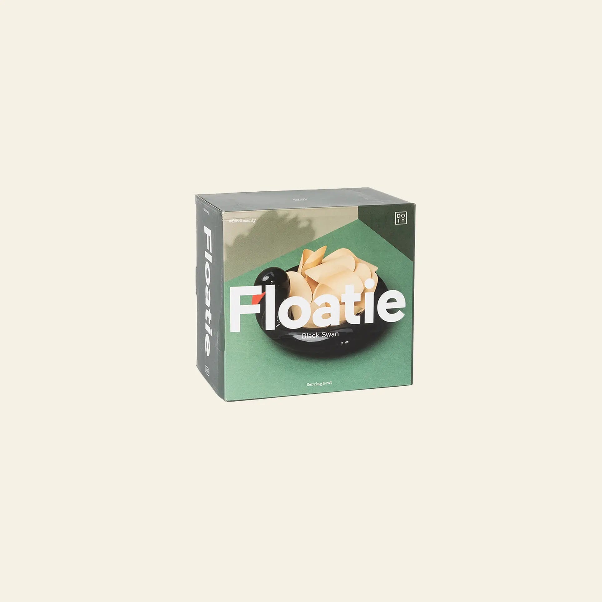 A box labeled DOIY showcases the Black Swan Floatie Bowl, featuring a tan origami-style ceramic bowl inside a black swan pool float, set against a green background—an ideal whimsical accent piece.