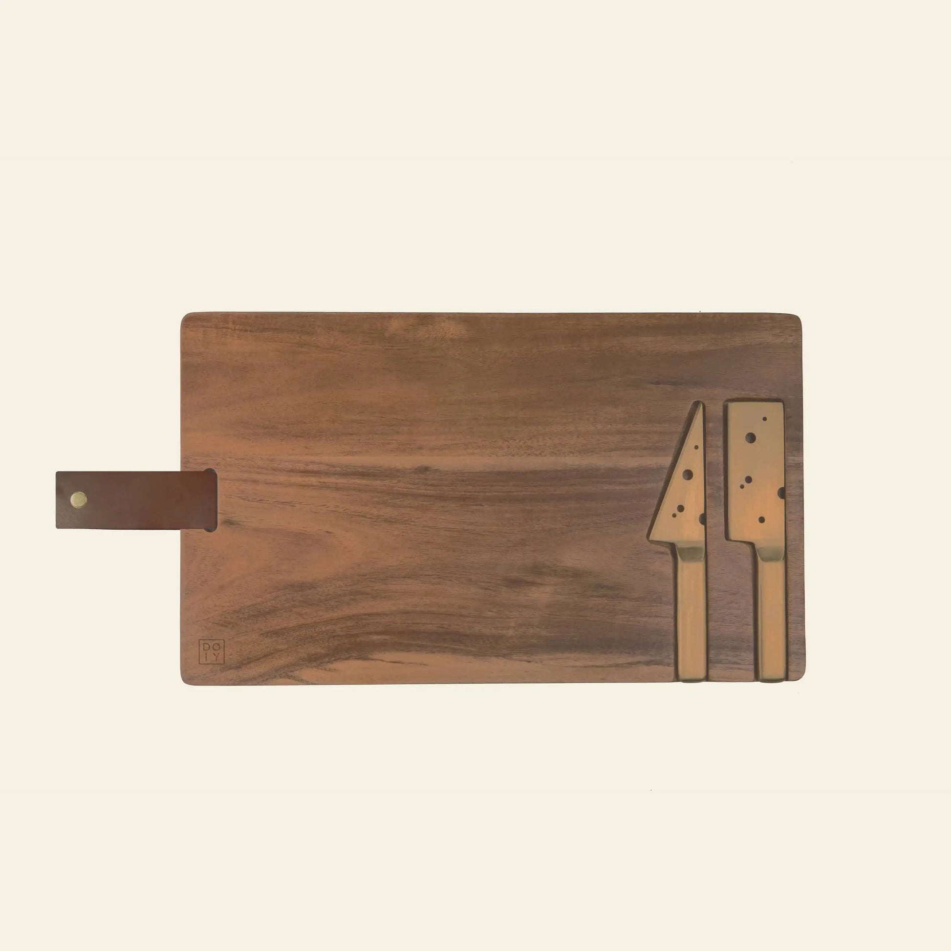 The DOIY Cheeseporn cheeseboard by DOIY, crafted from Acacia wood with a leather handle, rests on a light background. Two golden knives—one large and one small—are neatly arranged on the right side of the board.