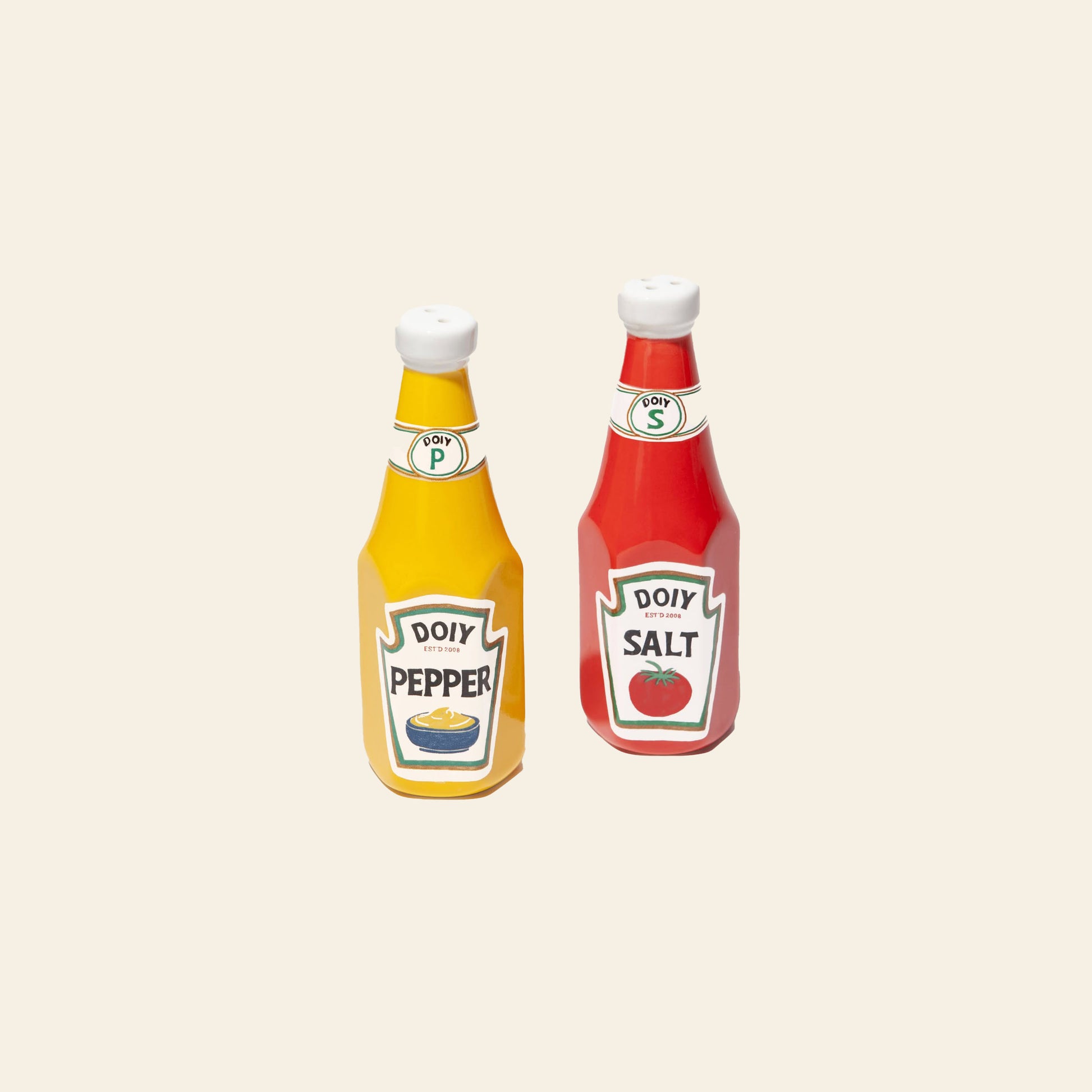 The DOIY Corner Shop Ketchup & Mustard Salt & Pepper Set by DOIY adds retro charm to your table with ceramic shakers styled as condiment bottles, featuring playful vintage graphics on a light background.