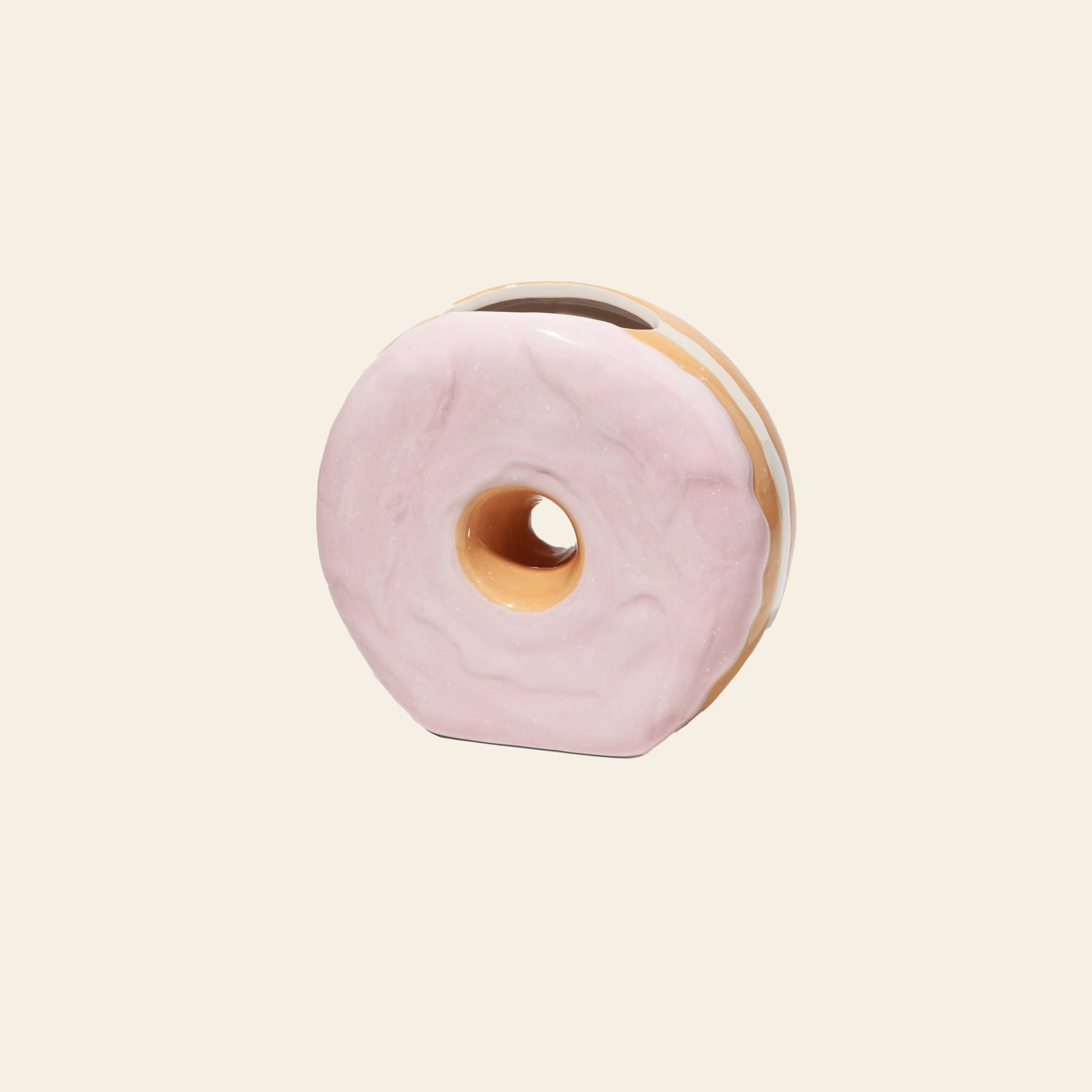 The DOIY Fast Food Donut Vase by DOIY is a ceramic vase shaped like a donut with a glossy pink glaze, shown against a plain beige background.
