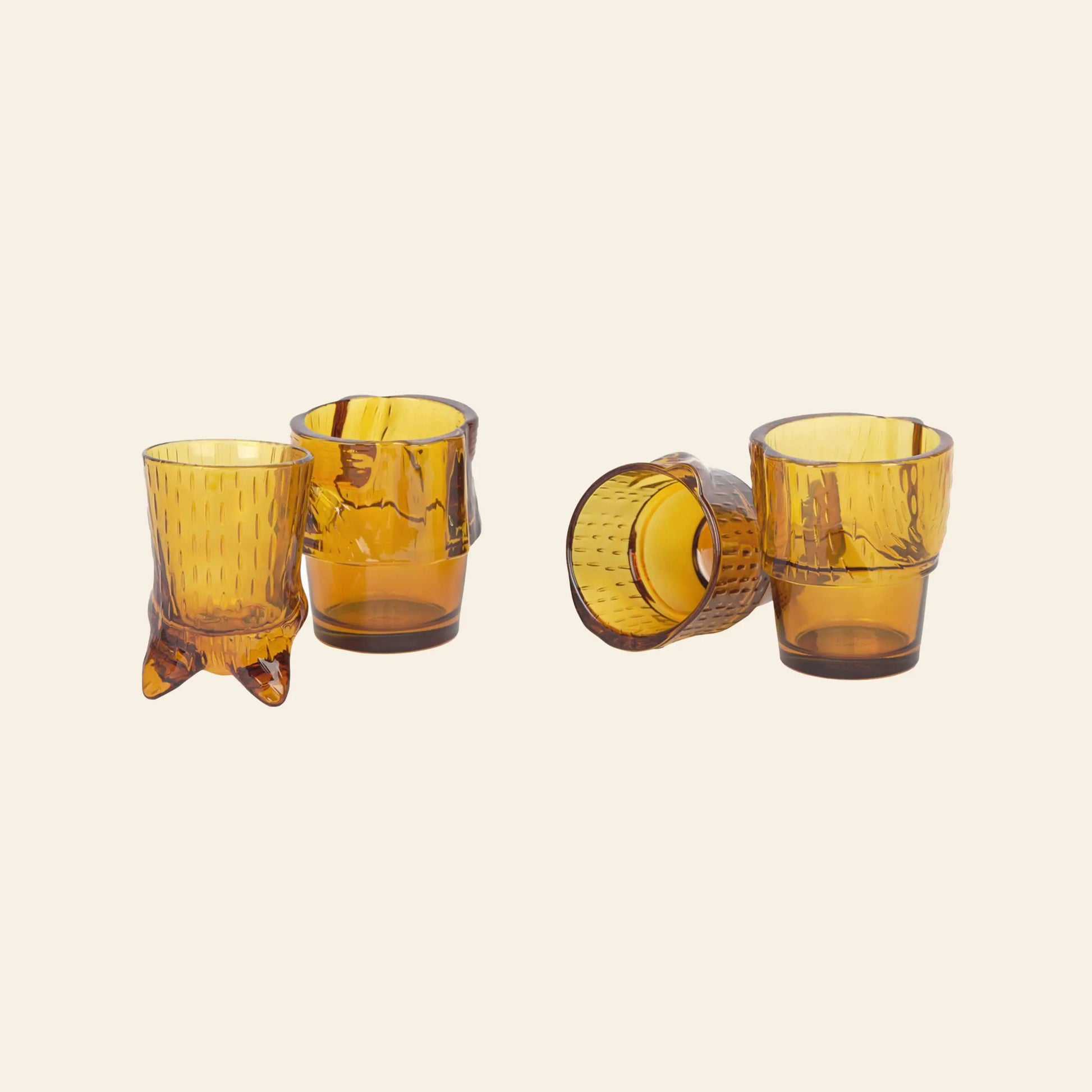 Four DOIY Kitty Glasses, each with a unique textured design and shape, are arranged in pairs on a light beige background, with some standing upright and others lying on their sides. This decorative set of 4 is by DOIY.