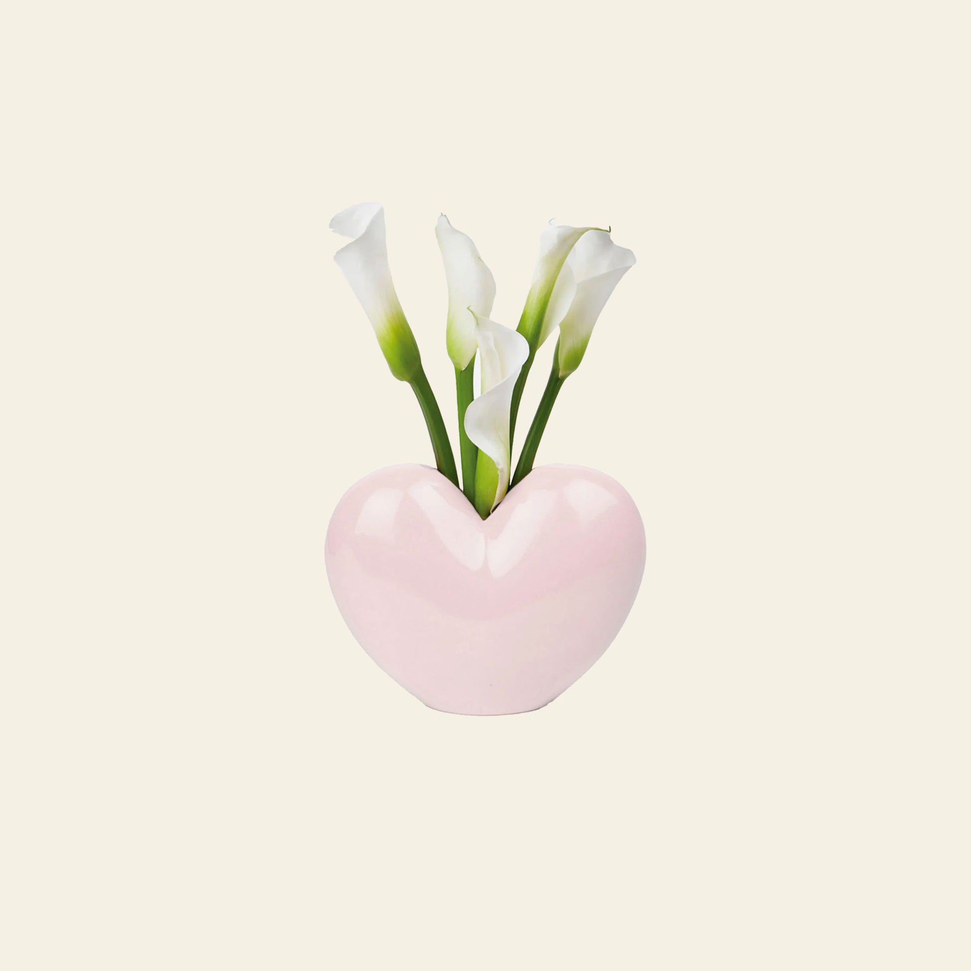 The DOIY Love Vase by DOIY features a pink, heart-shaped design holding white calla lilies with green stems, set against a light background—highlighting its sentimental style and elegant beauty.