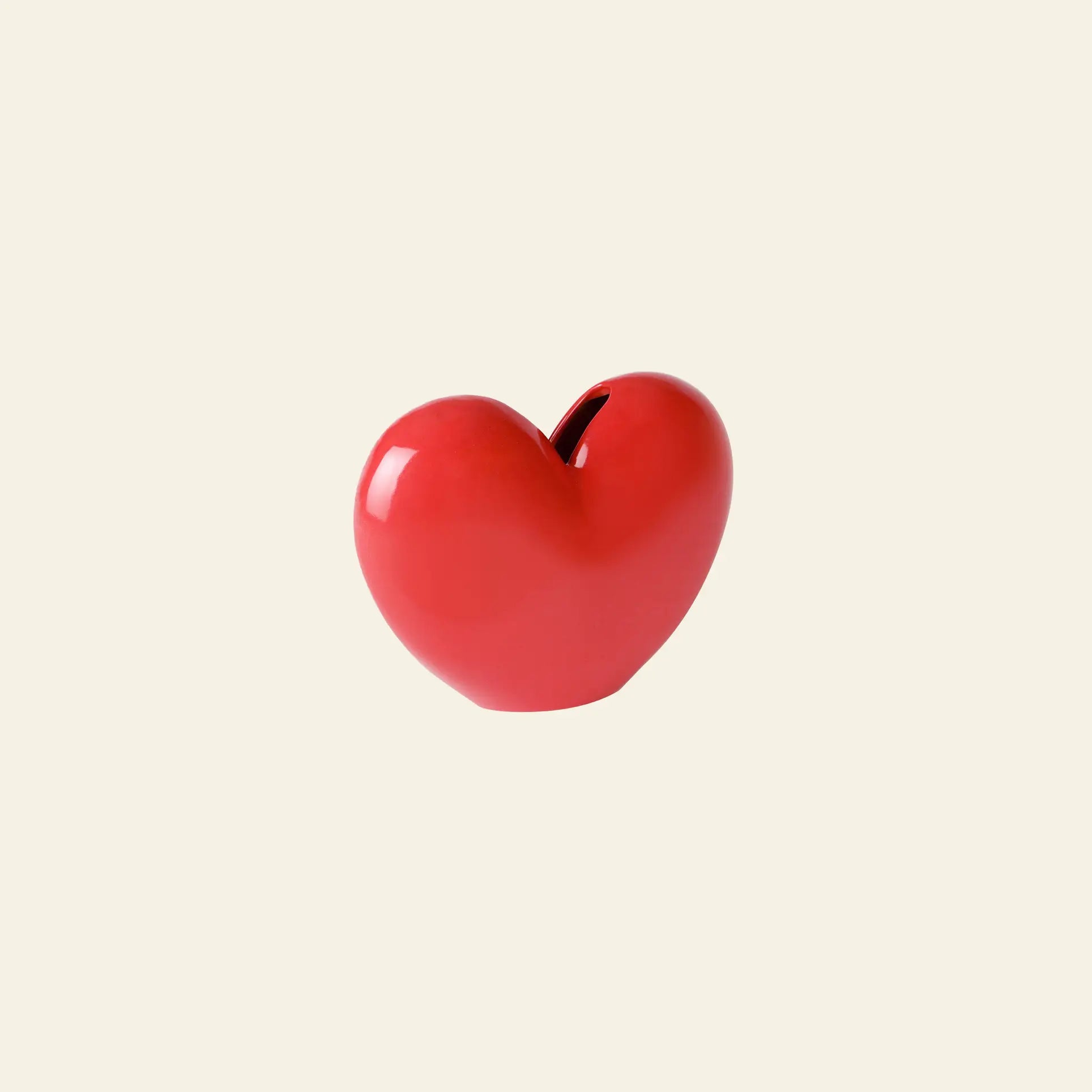 The DOIY Love Vase by DOIY is a glossy red ceramic heart-shaped vase, radiating timeless beauty with its sentimental design, displayed against a plain light beige background.
