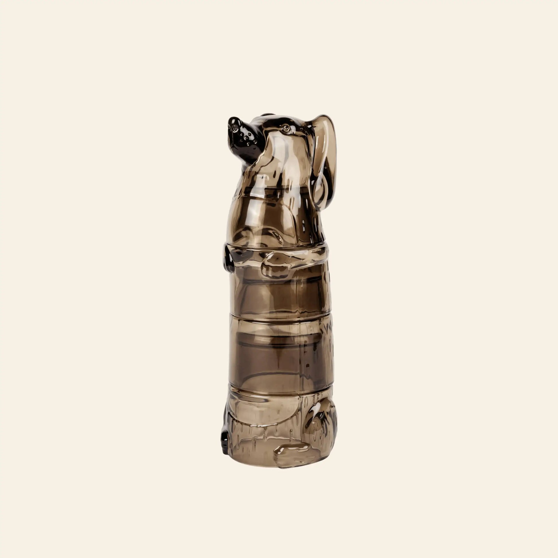 The DOIY Puppy Glasses, Set of 4 by DOIY feature glass bottles shaped like sitting dogs with front paws on barrels, in semi-transparent brown—ideal for collectors or fans of unique glassware. Shown against a light beige background.