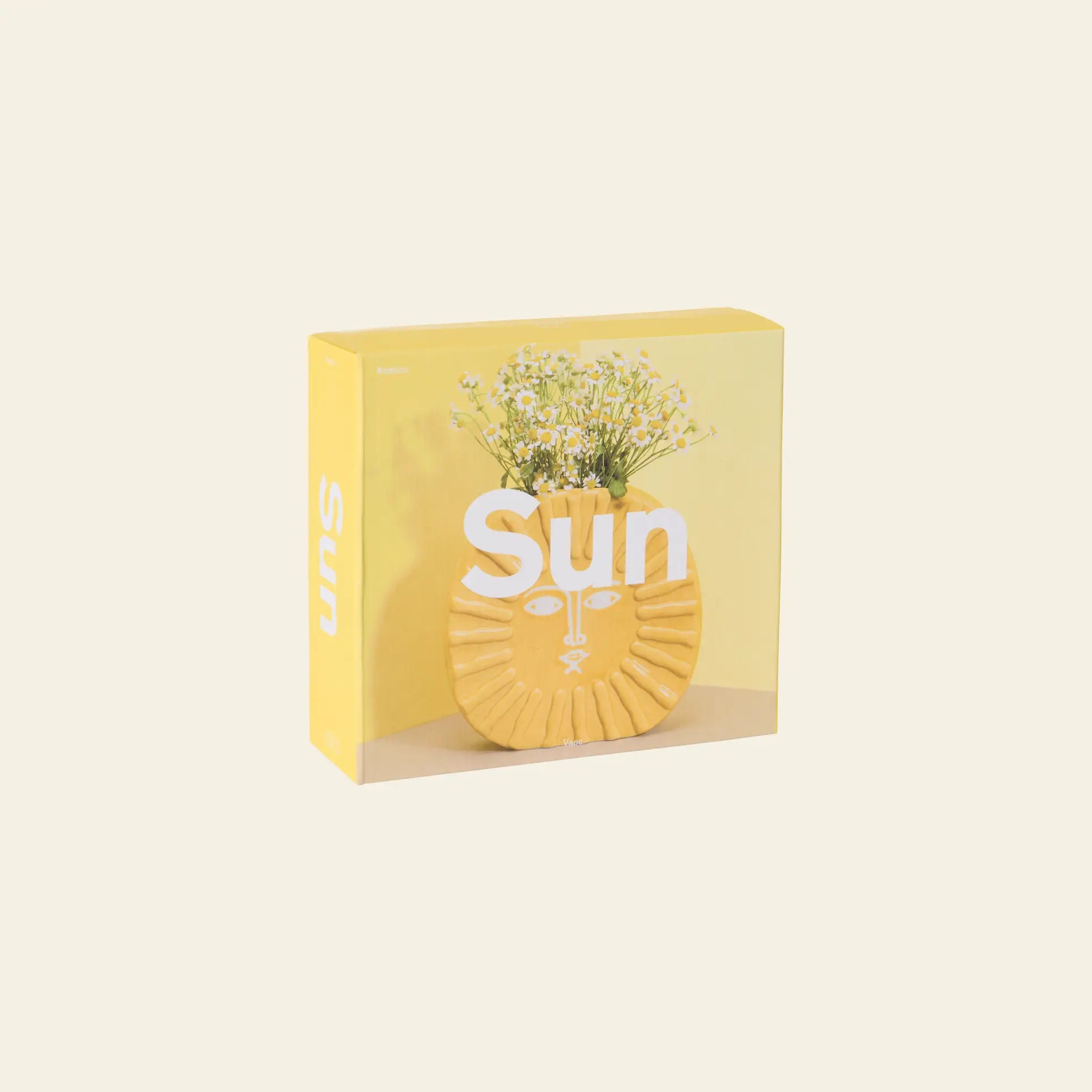 The DOIY Sun Vase by DOIY features a ceramic lion-face design filled with white flowers, displayed in a square yellow box with “Sun” in white text on the front—ideal for brightening up your home decor.