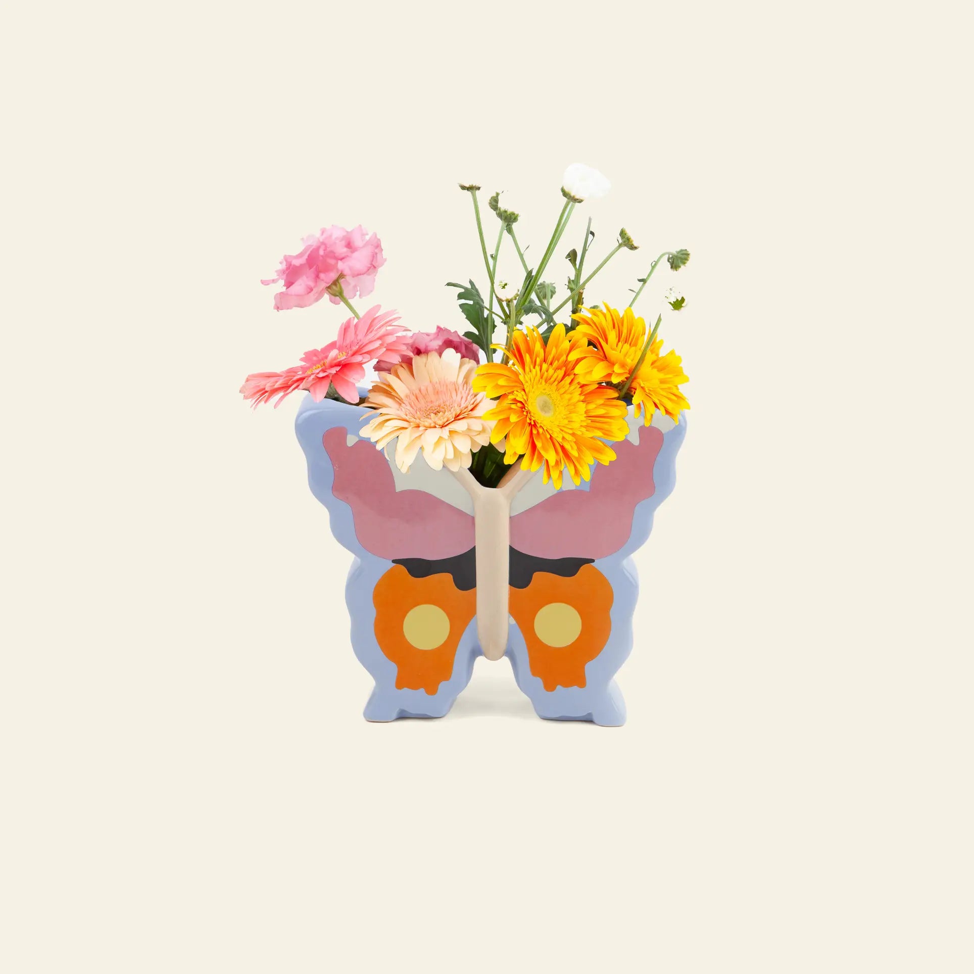 The DOIY Woodland Butterfly Vase by DOIY, featuring a colorful butterfly silhouette, holds vivid yellow, pink, and white flowers, bringing charm to a simple cream background.