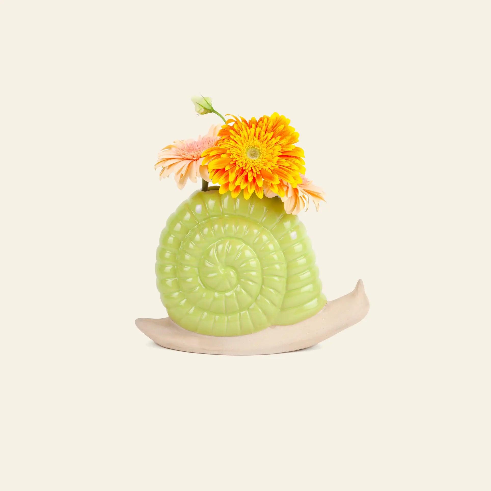 The DOIY Woodland Snail Vase by DOIY, in light green and beige ceramic, displays vibrant orange and pink flowers, creating a unique decorative accent against a plain off-white background.