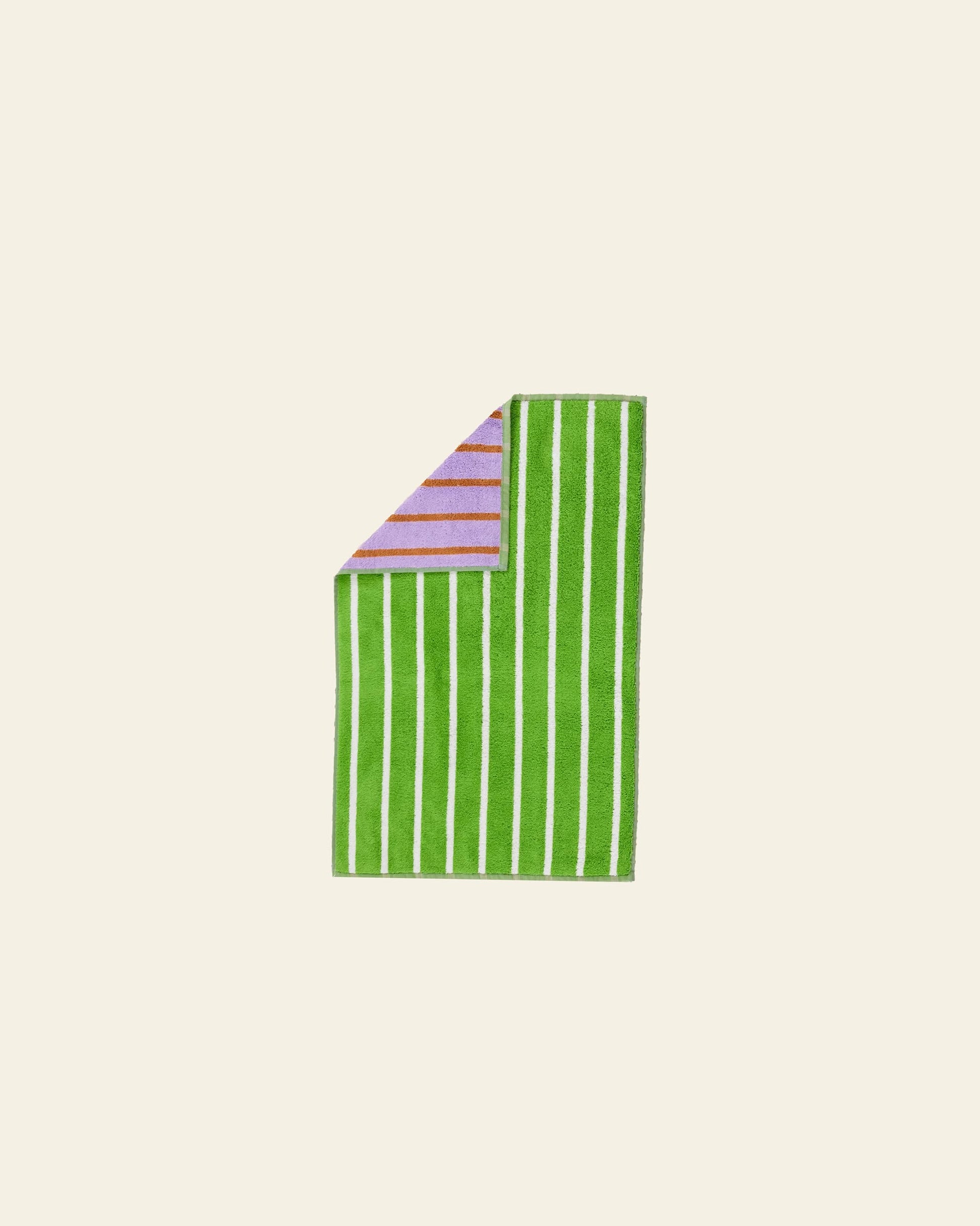 The Dusen Dusen House Stripe Glass Hand Towel features green and white vertical stripes. A folded corner reveals a purple side with horizontal lavender stripes, all set against a plain off-white background.