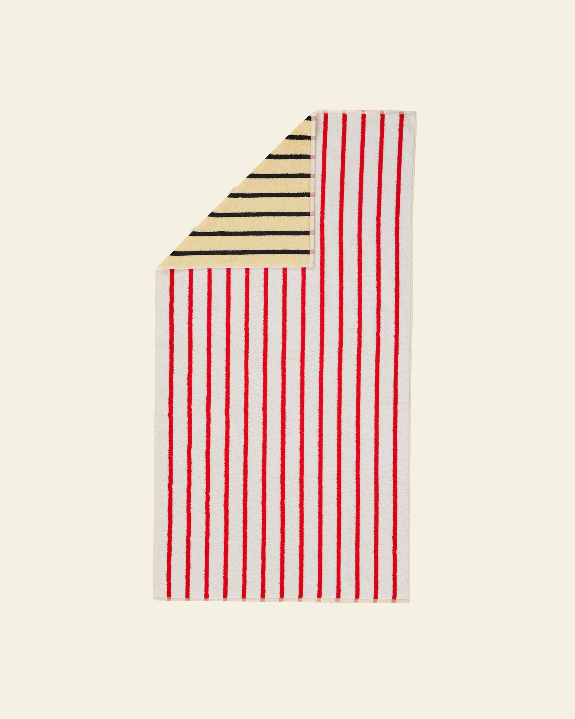 The Dusen Dusen House Stripe Stucco Bath Towel by Dusen Dusen showcases bold vertical red and white stripes on one side, with a folded corner revealing horizontal black and yellow stripes, all set against an off-white background.