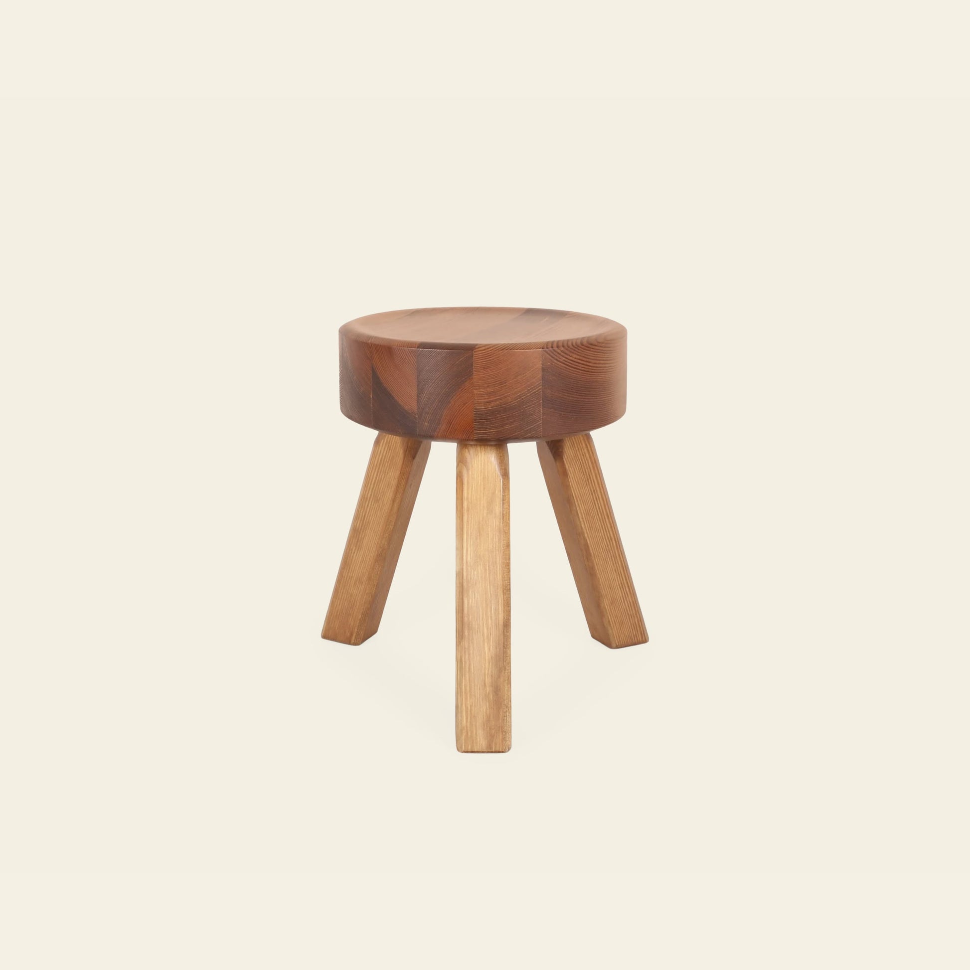 The FRAMA AML Stool by FRAMA features a thick, round seat and three angled legs in solid oiled pine. Its natural wood finish adds warmth and contrast to a plain off-white background.