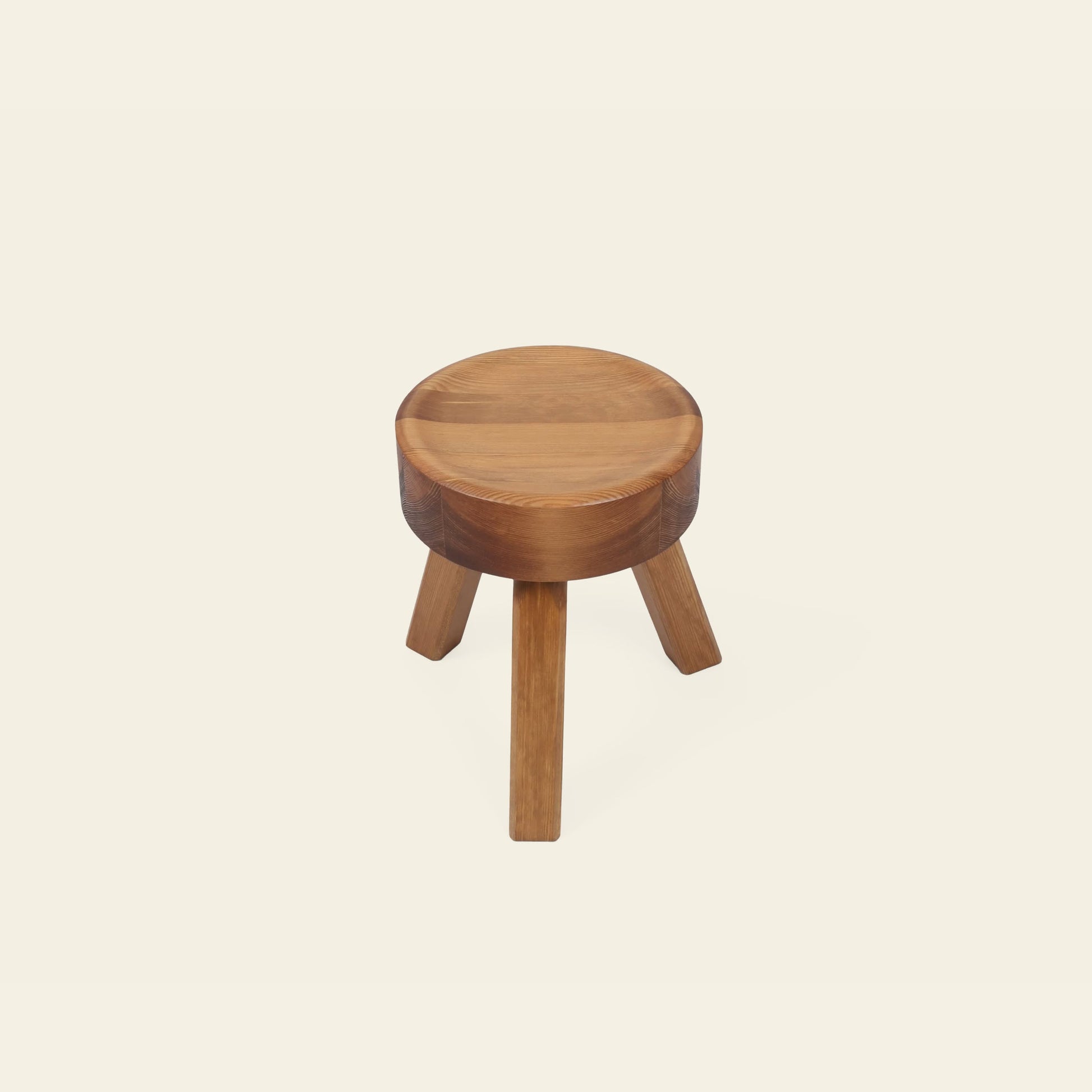 The FRAMA AML Stool by FRAMA is a compact bedside piece made from solid oiled pine, with a round seat and three legs, displayed on an off-white background.