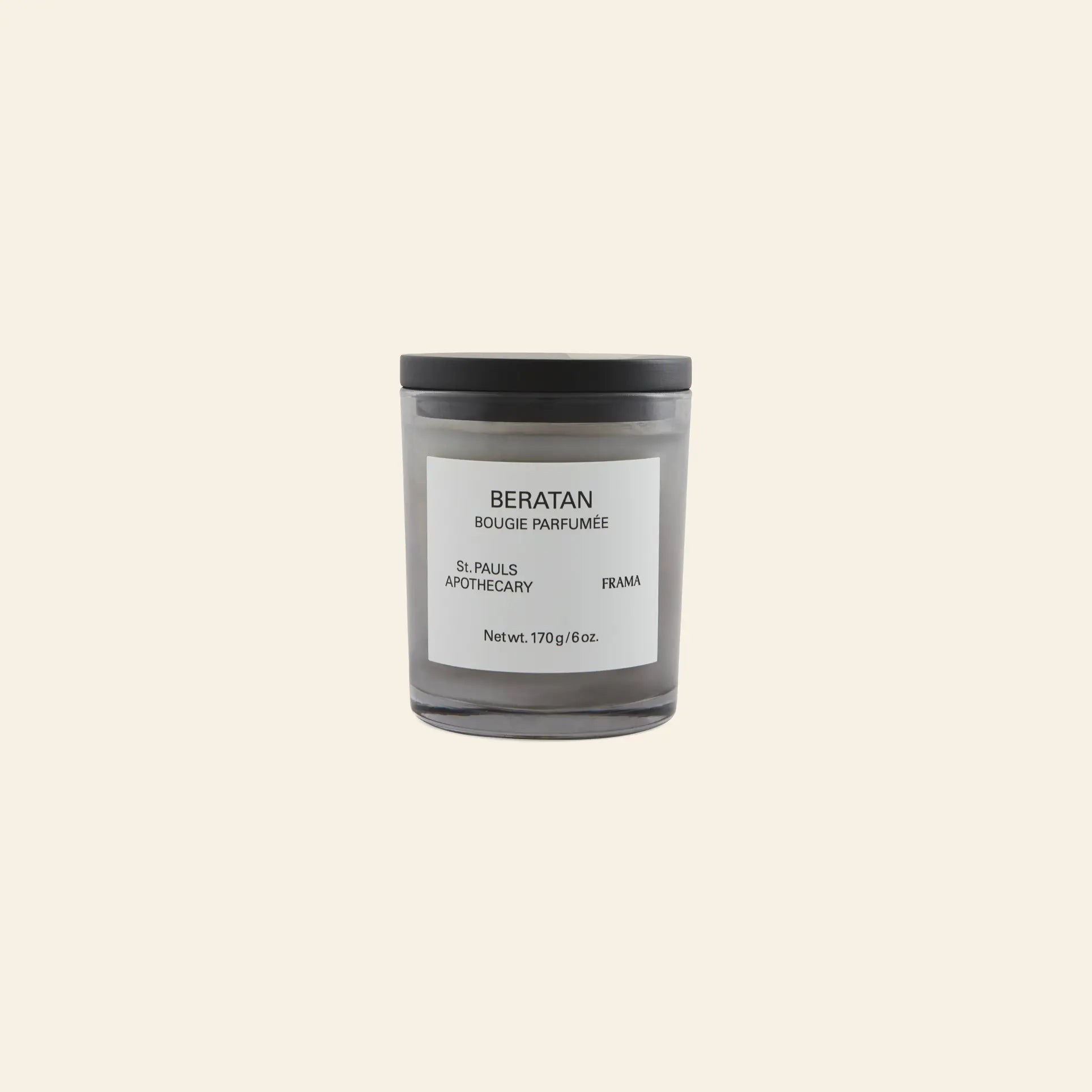 A gray FRAMA Beratan Scented Candle (170g) with a black lid and labeled BERATAN BOUGIE PARFUMÉE rests on a beige background, offering a warm fragrance with the signature Beratan scent.