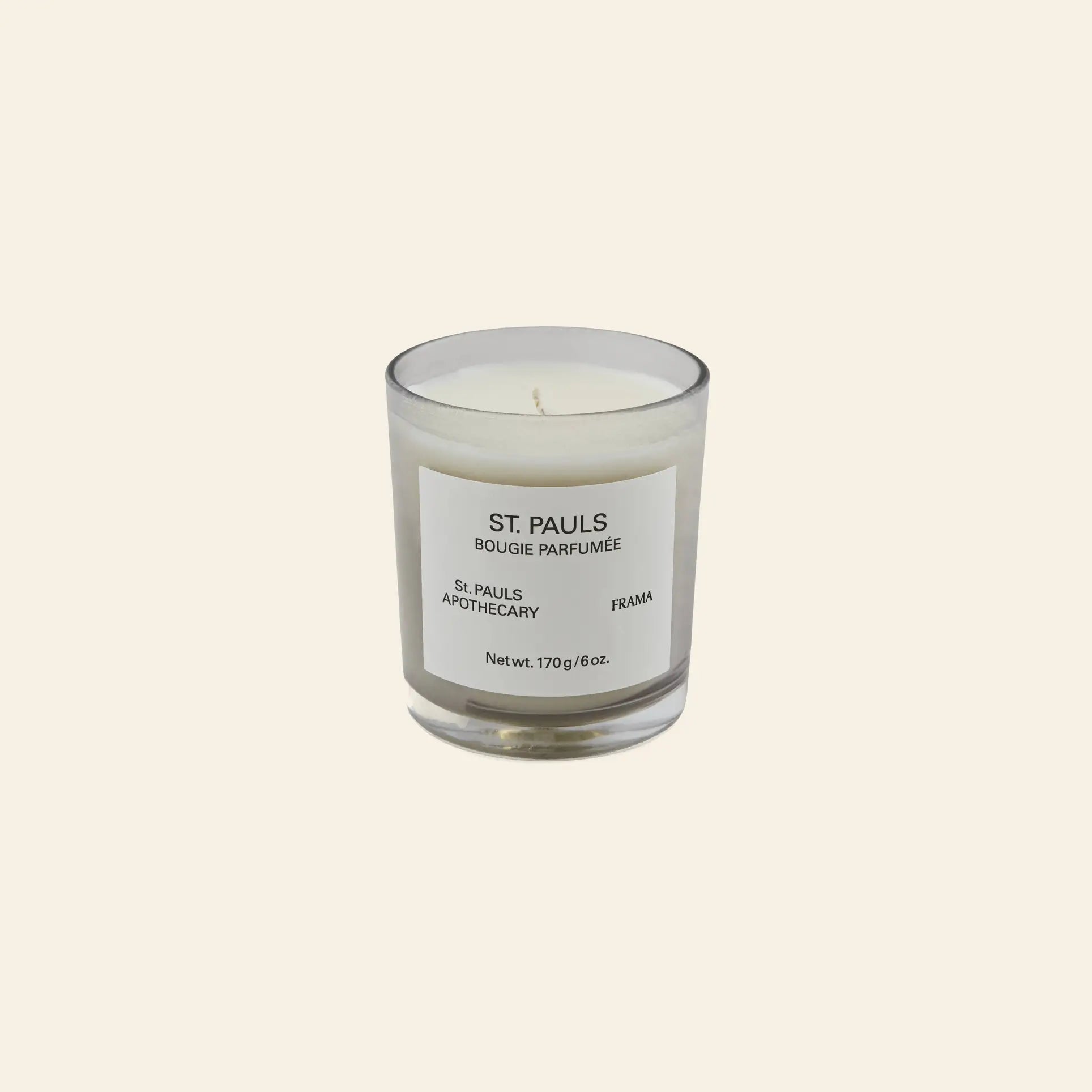 A FRAMA St. Pauls Scented Candle, 170g, sits in a clear glass jar with a minimalist label, displayed against a plain light beige background.