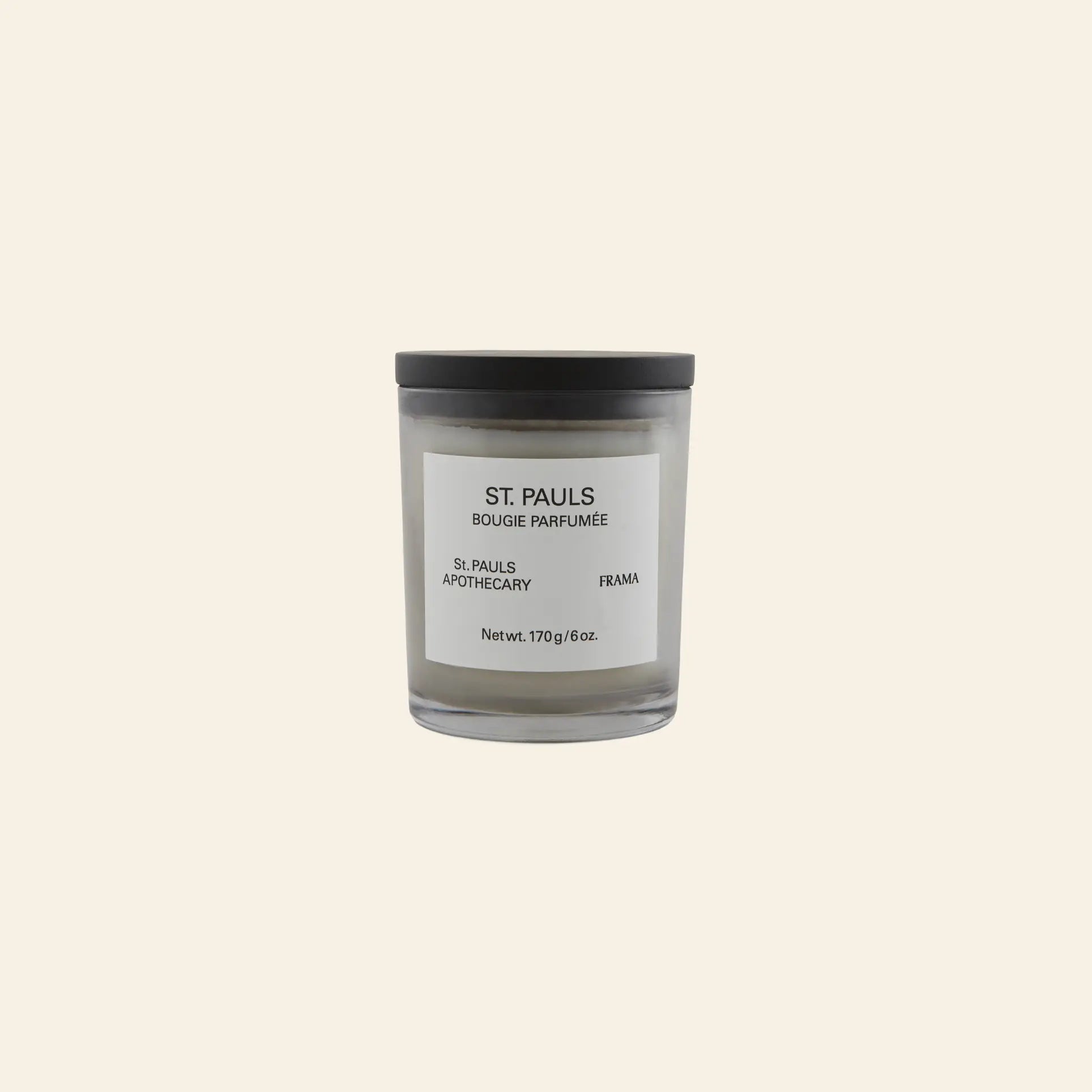 The FRAMA St. Pauls Scented Candle, 170g, in a glass jar with a black lid and minimalist white label, is displayed against a beige background.
