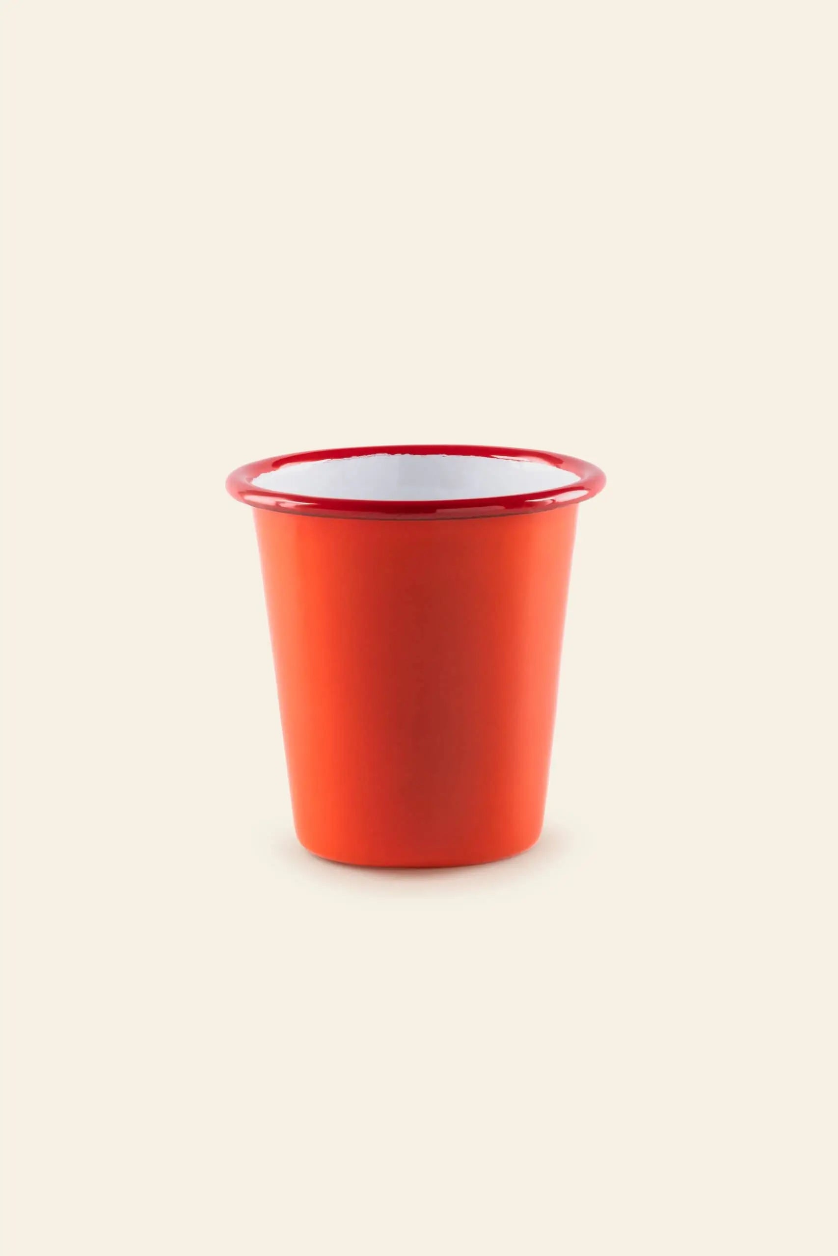 The Falcon Enamelware Tumbler by Falcon Enamelware is a small, bright red enamel tumbler with a white interior and red rim, shown centered on a plain beige background.