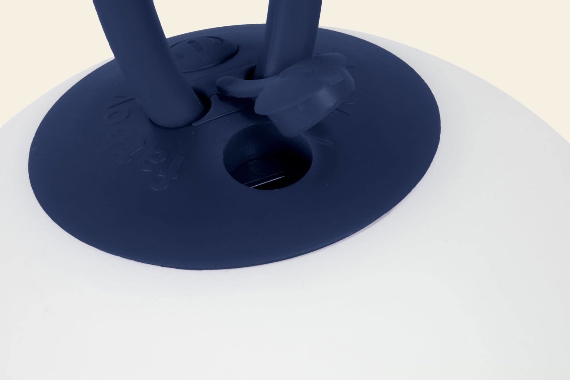 Close-up of the Fatboy Bolleke, a white light by Fatboy with a round, dark blue rubber base and embossed text. Two upright handles—one with a blue ring—highlight the brands signature contemporary style.