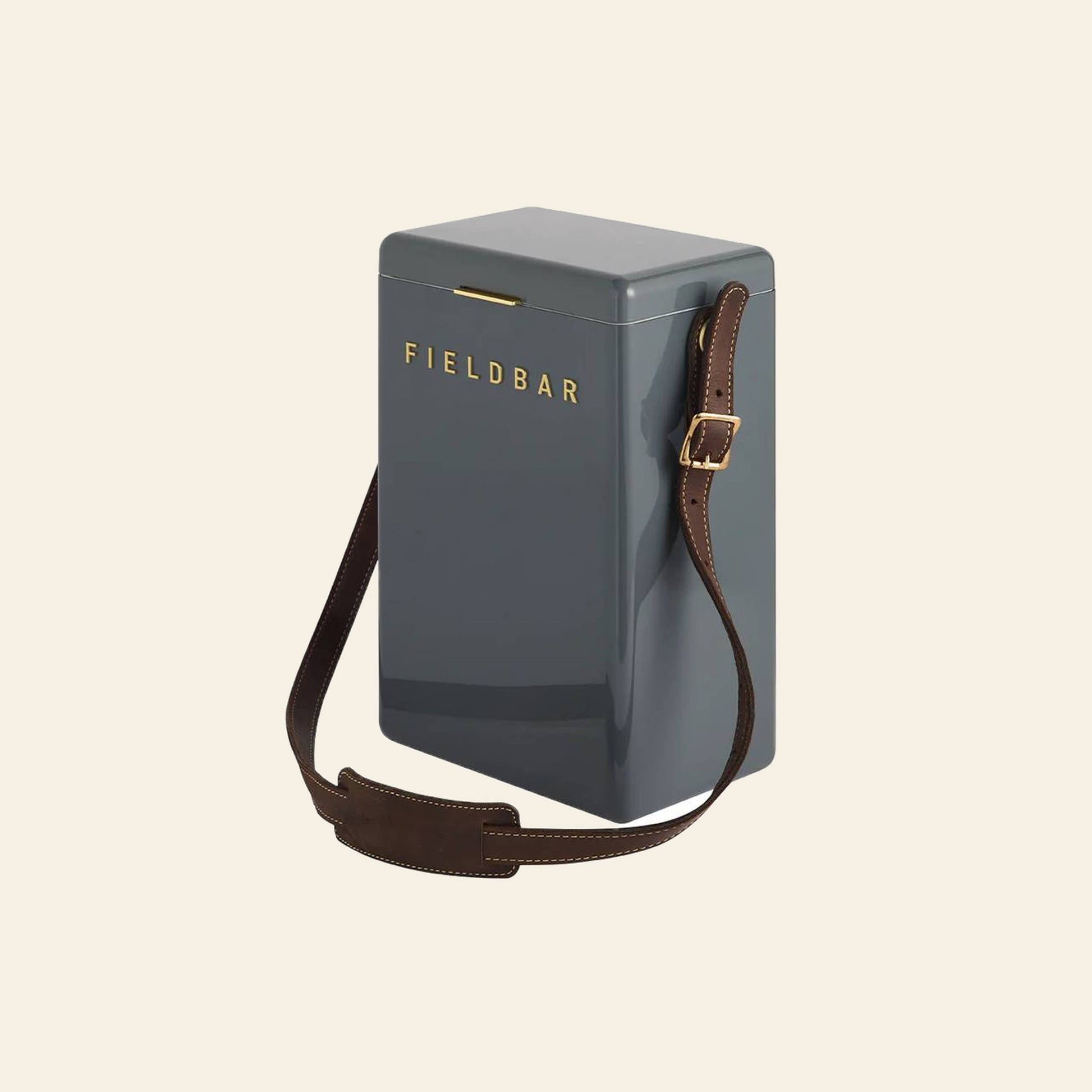 The Fieldbar Drinks Box Sling—rectangular, dark gray, with a premium brown leather adjustable strap and gold buckle—is a stylish hands-free cooler for outings from Fieldbar. Set against a plain light background.