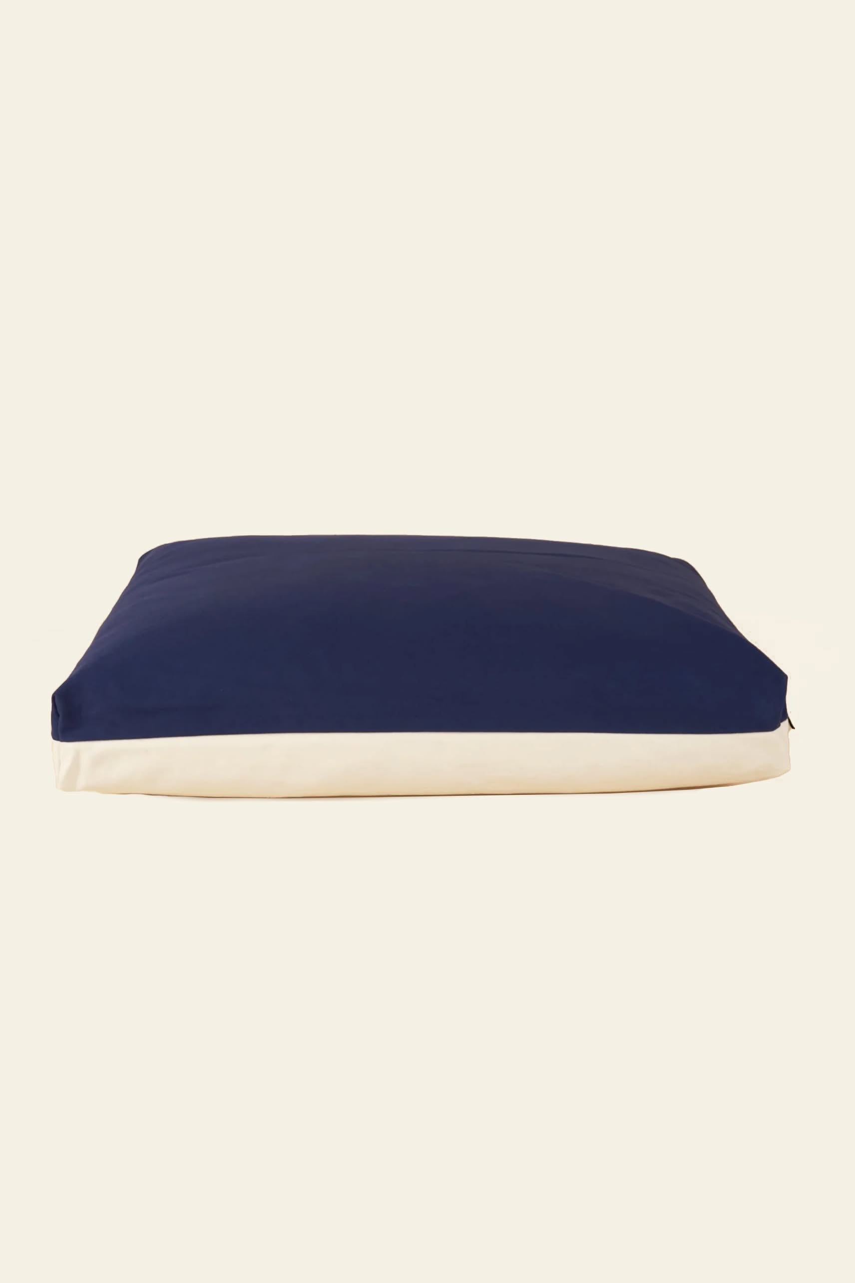 The Good Chonk Cloud Kapok Dog Bed features a rectangular shape, dark blue top, and white sides. Made by Good Chonk with a 100% cotton canvas cover and eco-friendly kapok fill, it’s pictured against a plain light background.