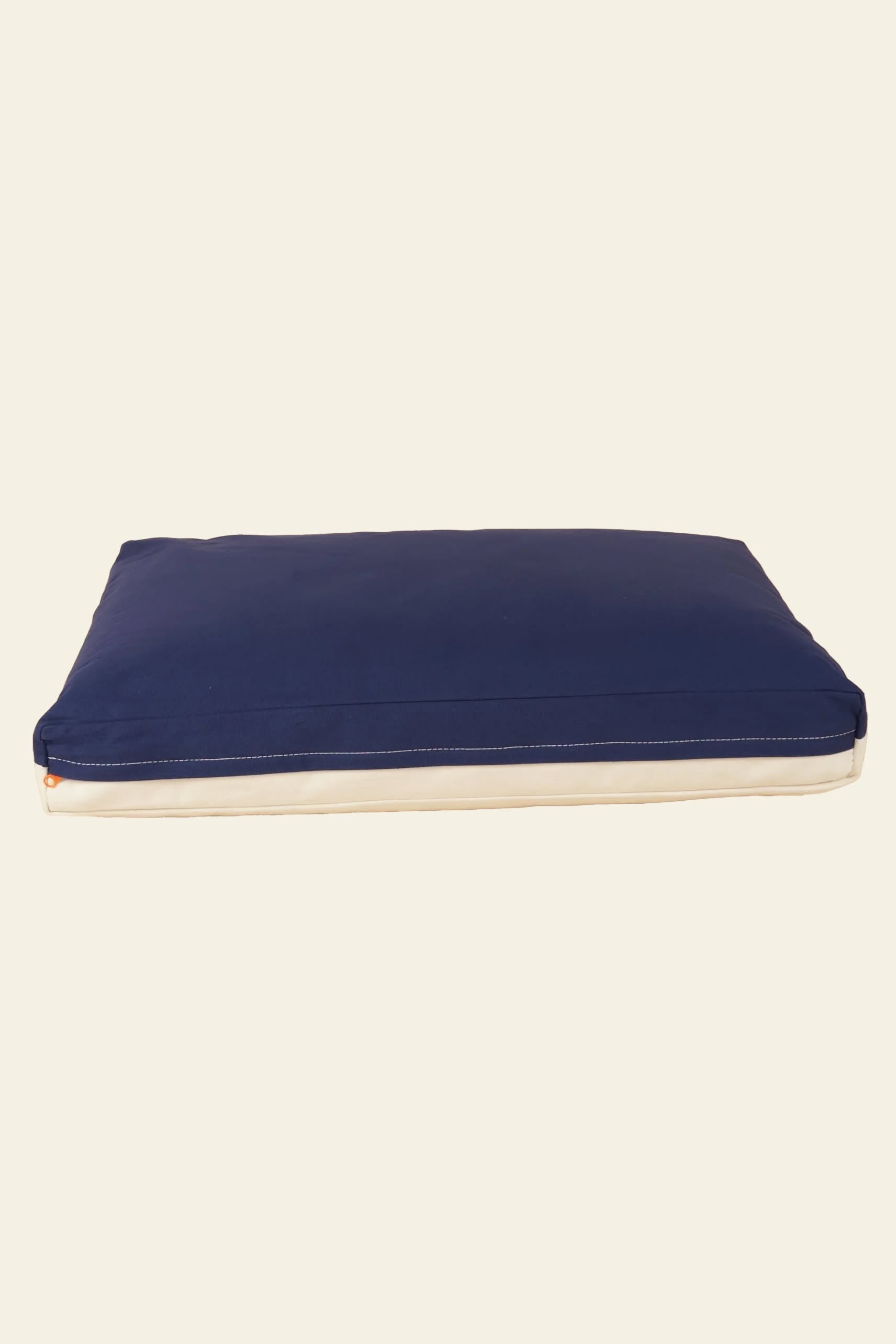 The Good Chonk Cloud Kapok Dog Bed by Good Chonk features a rectangular shape with a dark blue top, white sides, an eco-friendly kapok fill, and a 100% cotton canvas cover, shown against a plain light background.