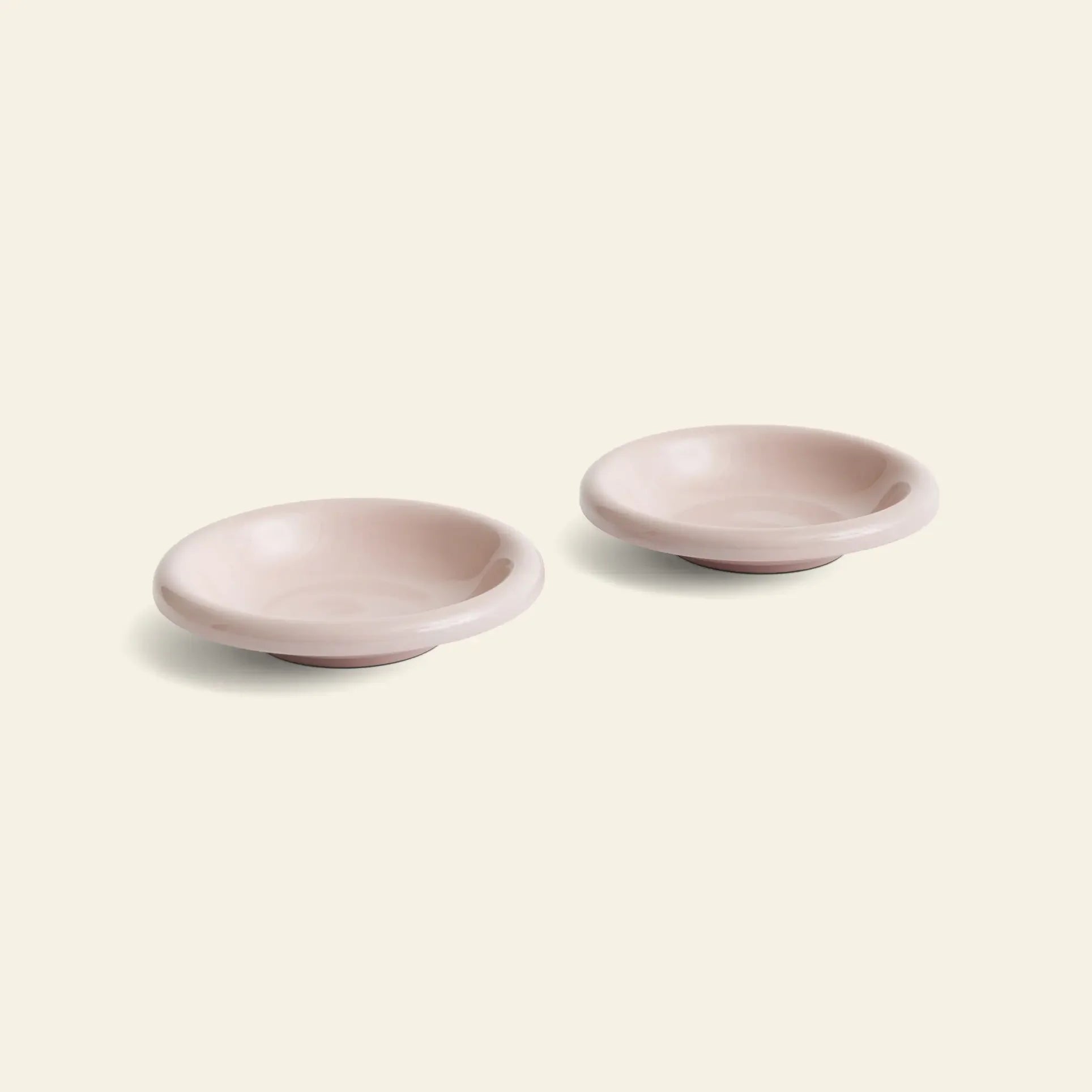 Two light pink HAY Barro Bowls, Set of 2 by HAY, inspired by classic Barro designs, are placed side by side on a plain off-white background.