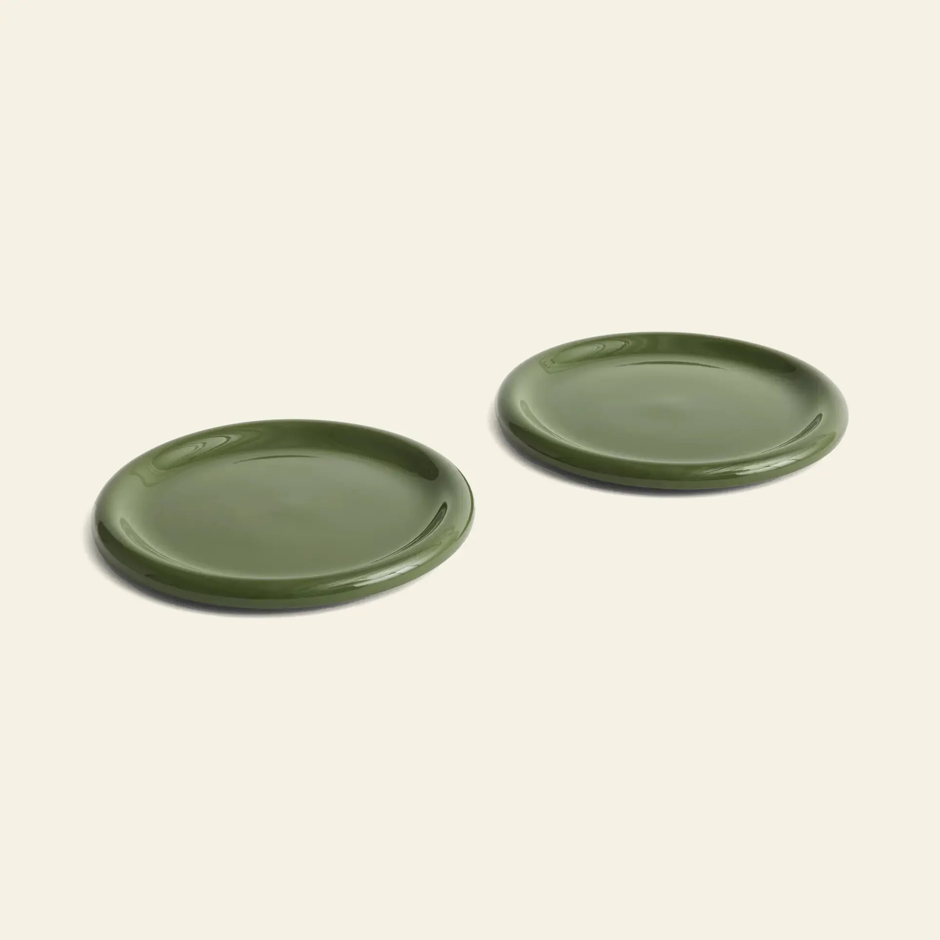 A set of two HAY Barro Plate 24cm green ceramic plates from HAY are displayed side by side on a plain, light beige background.