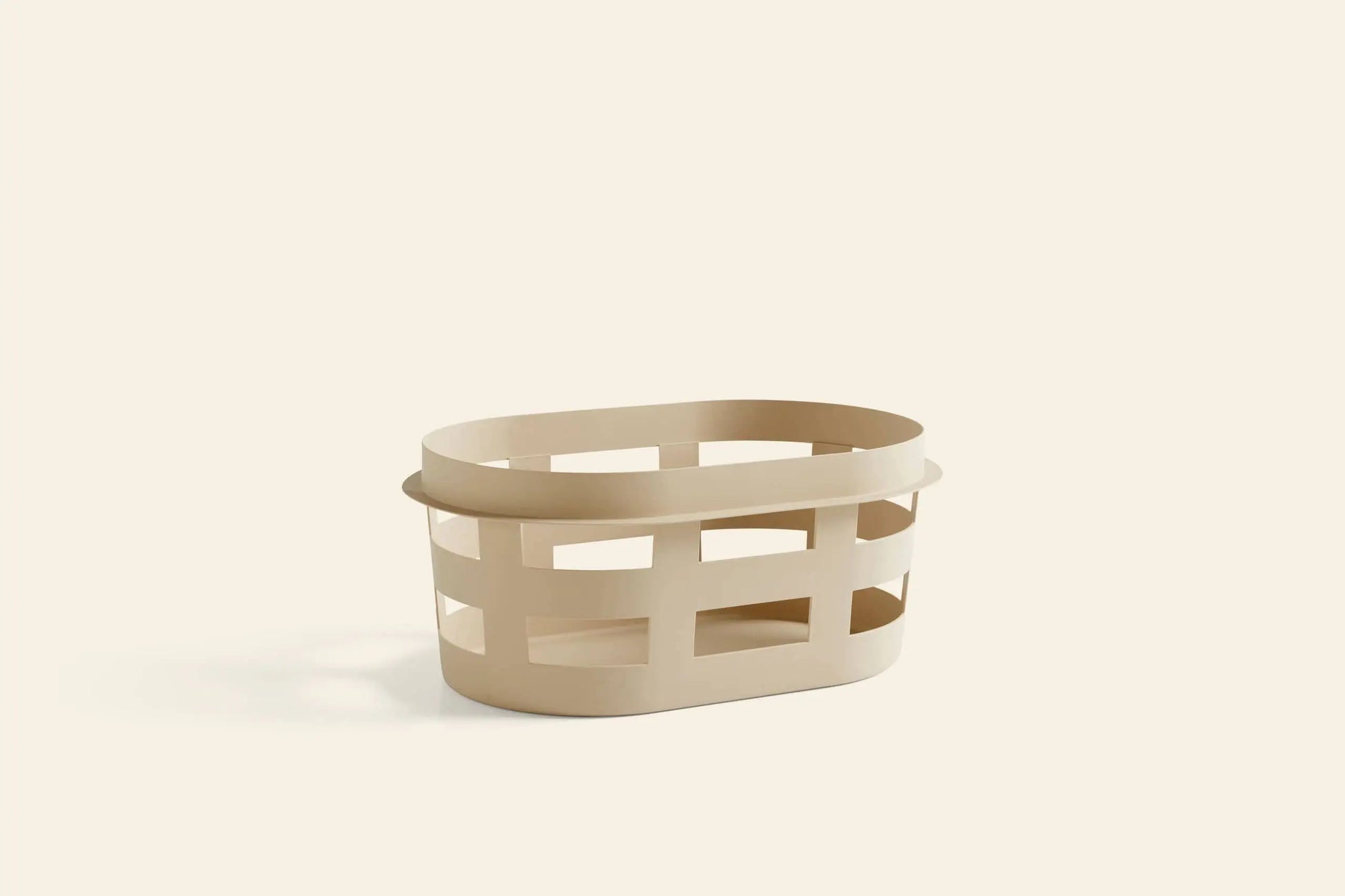 The HAY Basket S by HAY is a beige, oval-shaped plastic laundry basket with wide rectangular side cutouts, shown on a plain light background.