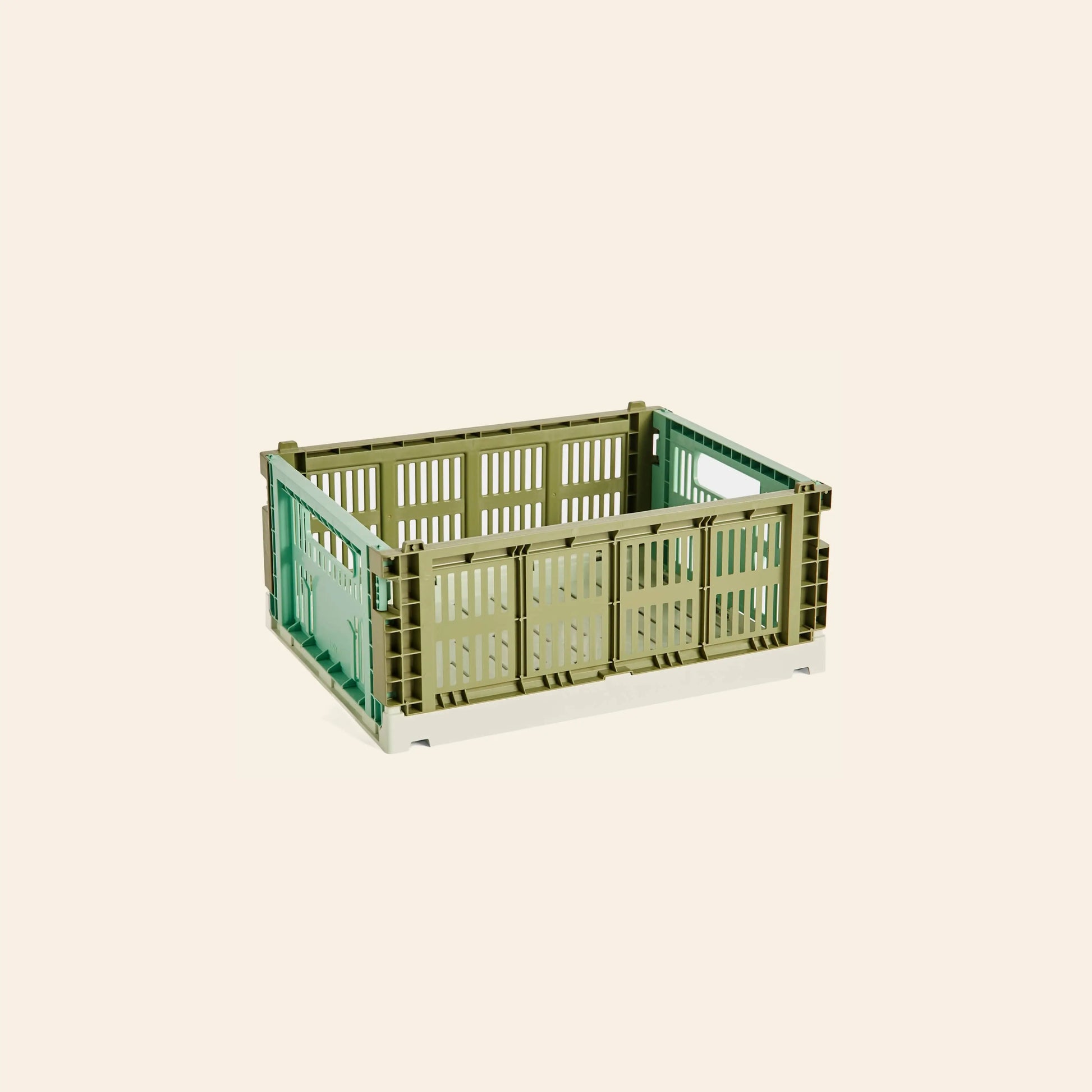The HAY Colour Crate Mix Medium storage box by HAY, crafted from recycled plastic with slatted green and beige sides, is shown on a light beige background.