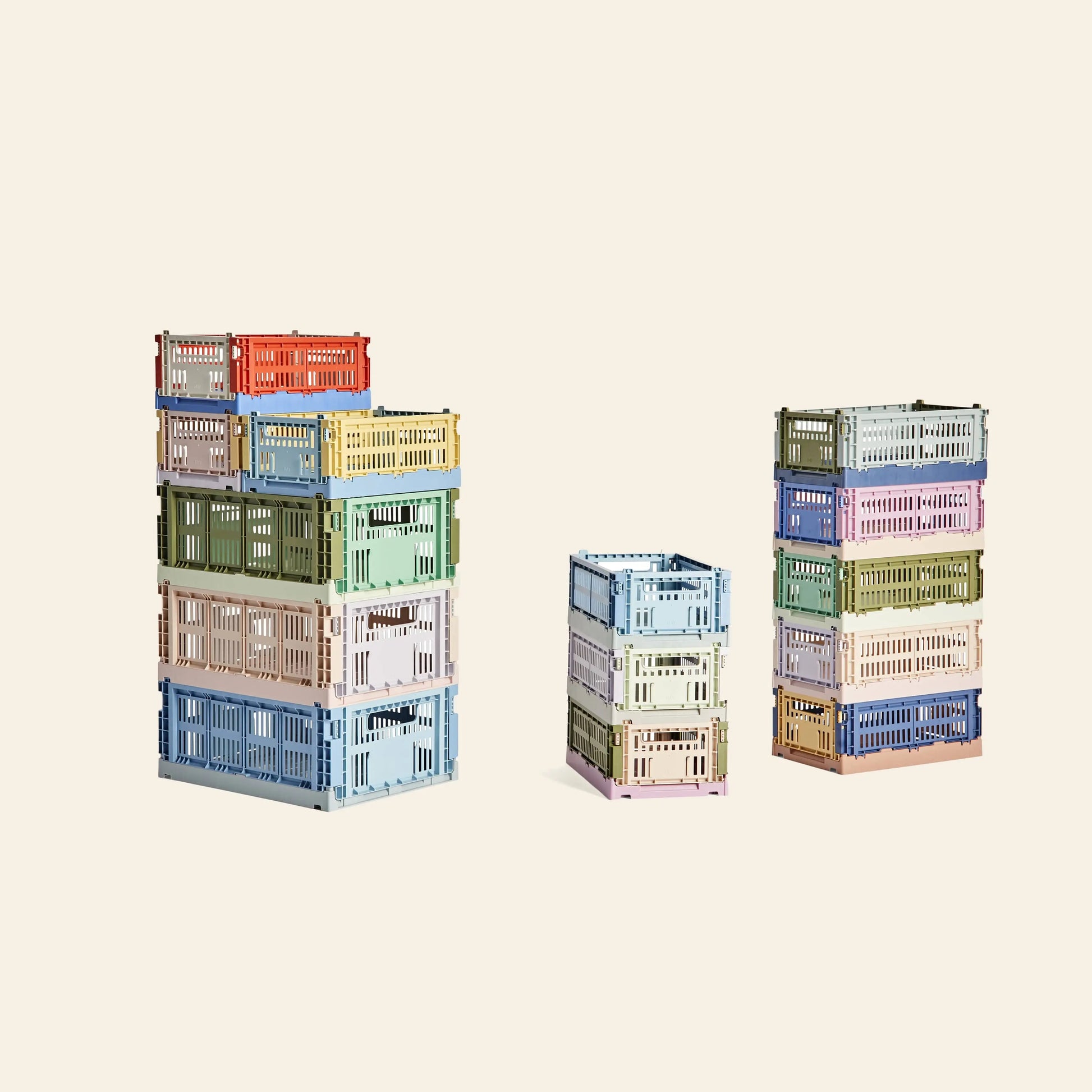 Four HAY Colour Crate Mix Medium storage boxes, crafted from recycled plastic, are stacked at varying heights against a beige background. The crates by HAY display an orderly arrangement in assorted pastel tones.