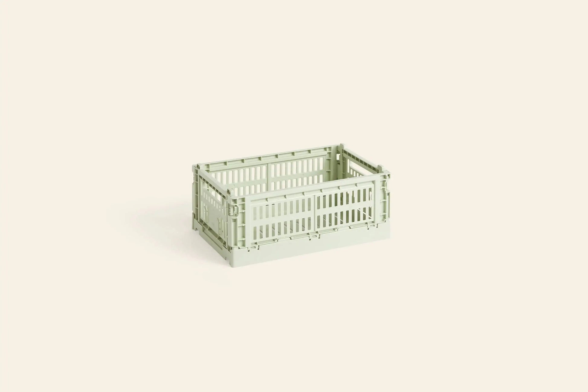 The HAY Colour Crate Small by HAY is a light green, rectangular plastic storage crate with slotted sides, shown on an off-white background—ideal for stylishly organizing any space.