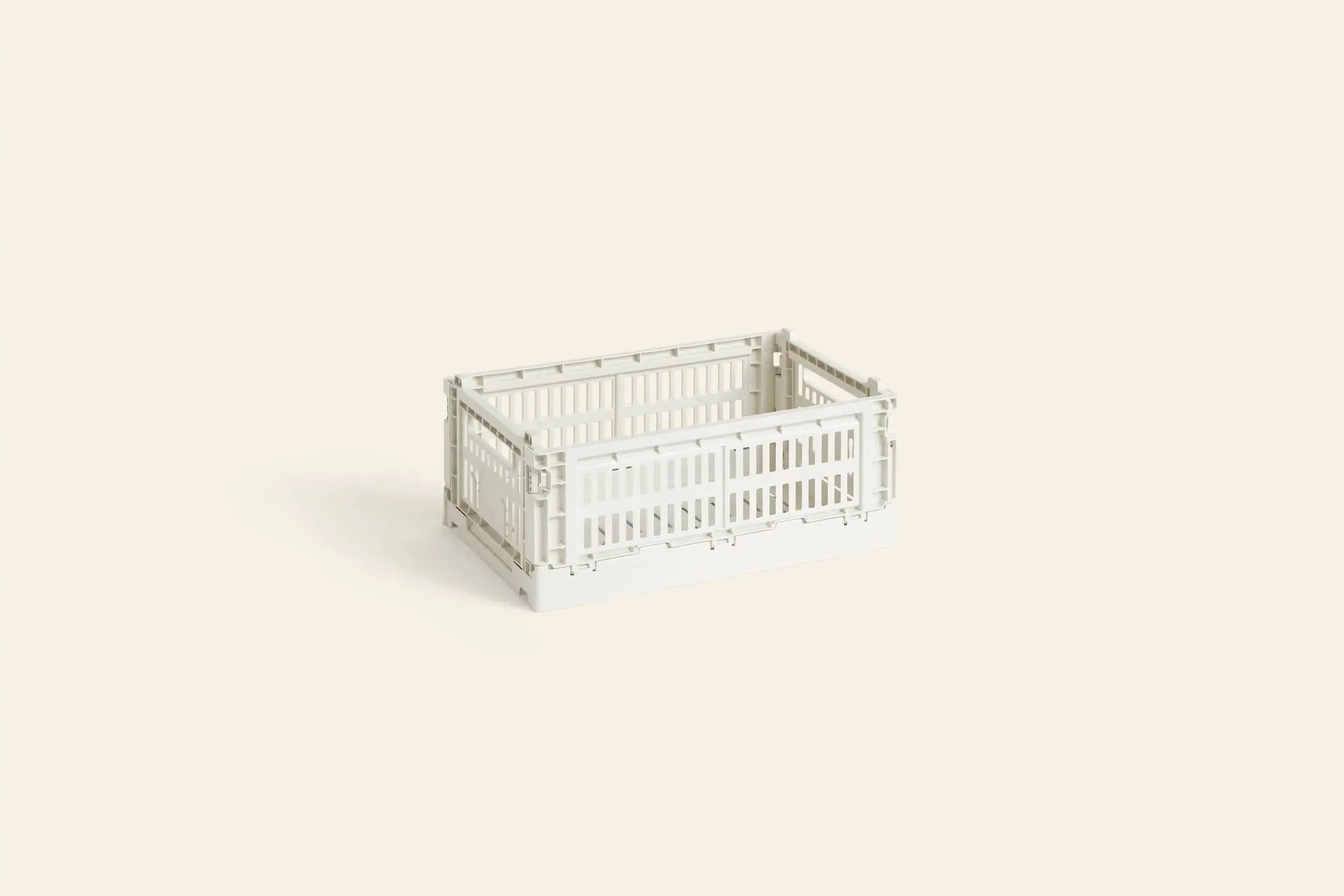 The HAY Colour Crate Small by HAY, shown here in white with a rectangular shape, stands on a light beige background, creating an organized and minimalistic look for any space.