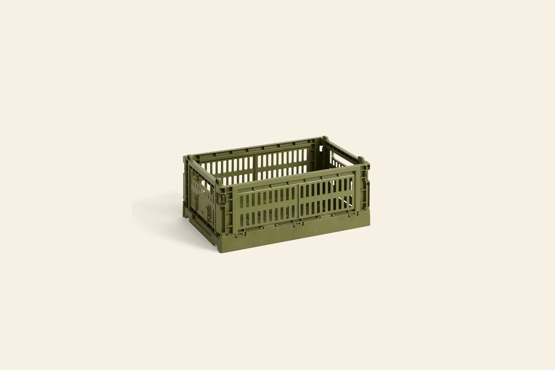 A small, rectangular olive green HAY Colour Crate Small by HAY, featuring open slats for stylish storage, is displayed on a plain light beige background.
