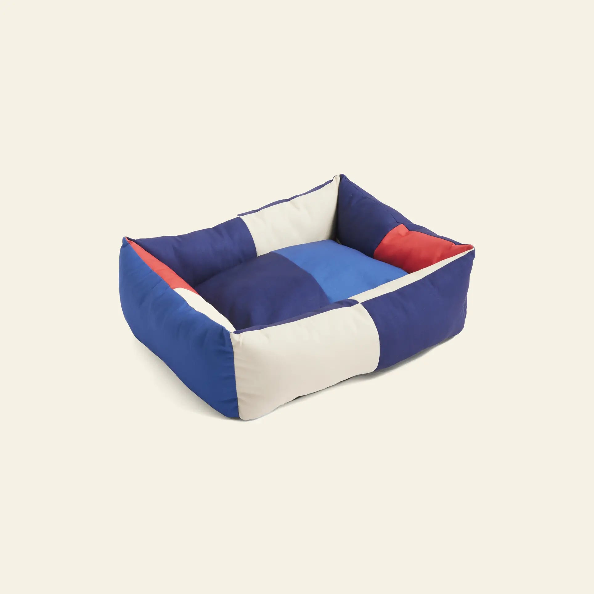 The HAY Dogs Bed M by HAY features a rectangular shape with raised sides, crafted from recycled polyester in a blue, white, and red patchwork design.