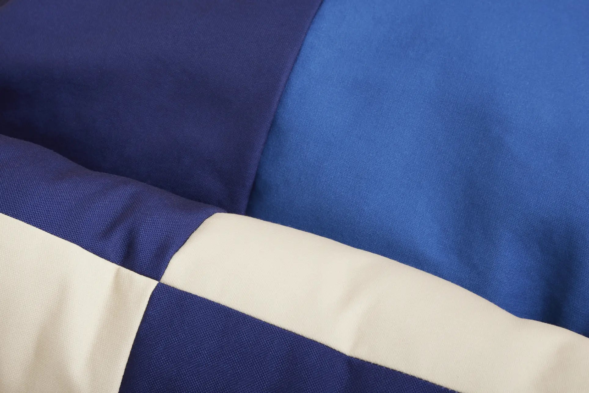 Close-up of the HAY Dogs Bed M by HAY, crafted from recycled polyester with large navy blue, royal blue, and cream geometric blocks—an eco-friendly and stylish choice for your pet.