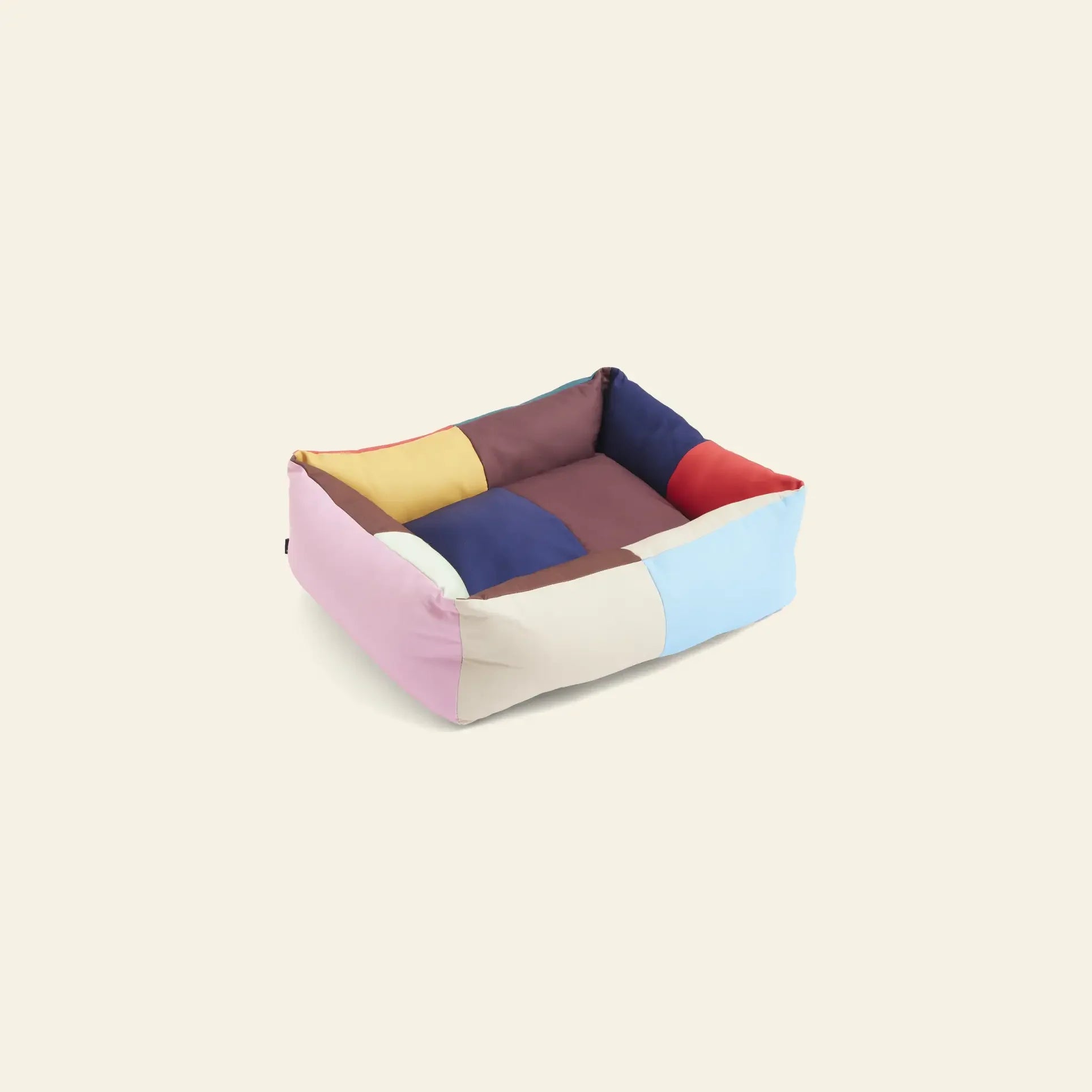 The HAY Dogs Bed S by HAY is a rectangular dog bed with raised sides, showcasing a pastel patchwork in pink, yellow, brown, blue, red, and beige, and made from recycled polyester for colorful pet space accessories.
