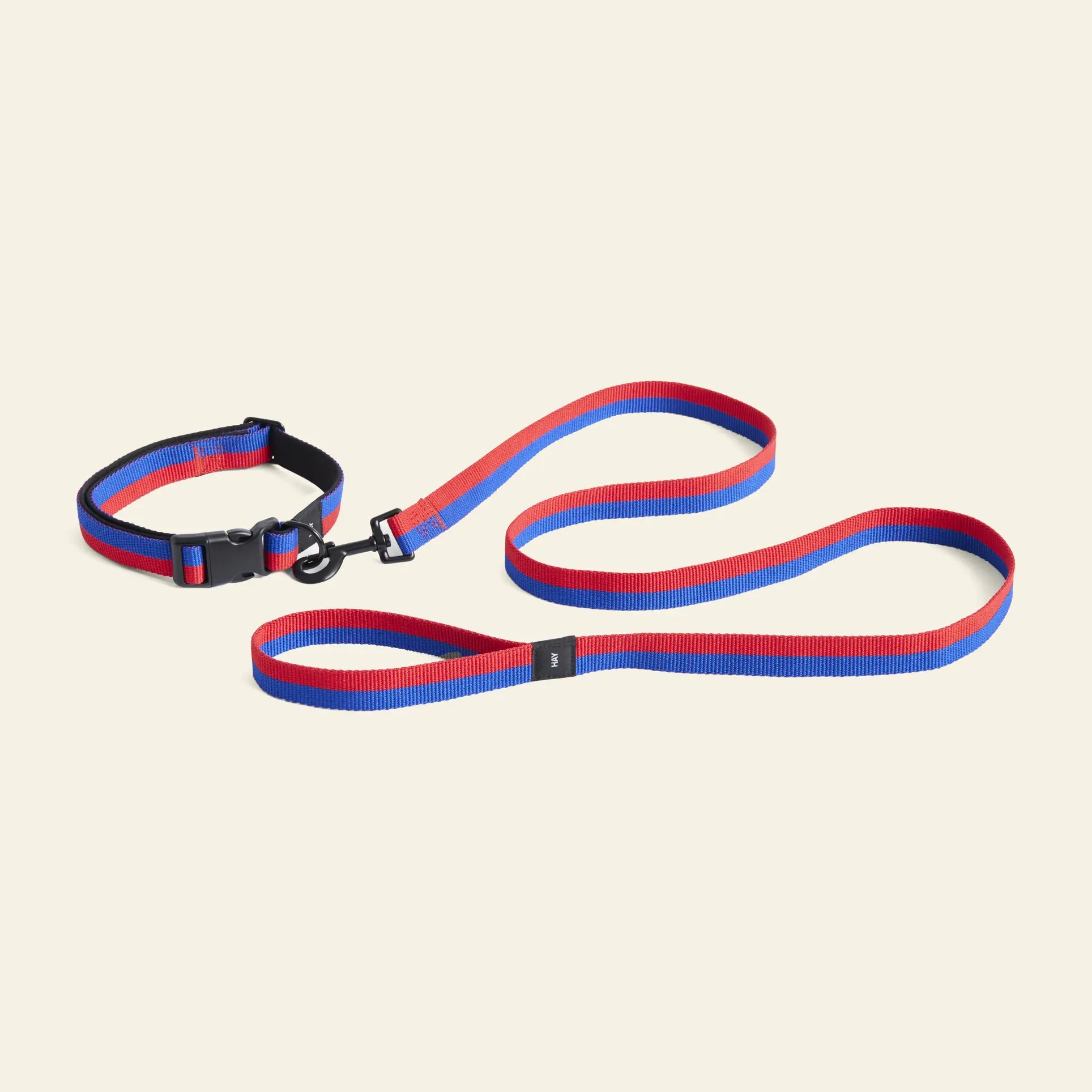 A blue and red striped pet collar and the HAY Dogs Leash Flat M/L by HAY, both woven from recycled polyester, are shown on a light beige background—perfect stylish accessories for your dog.