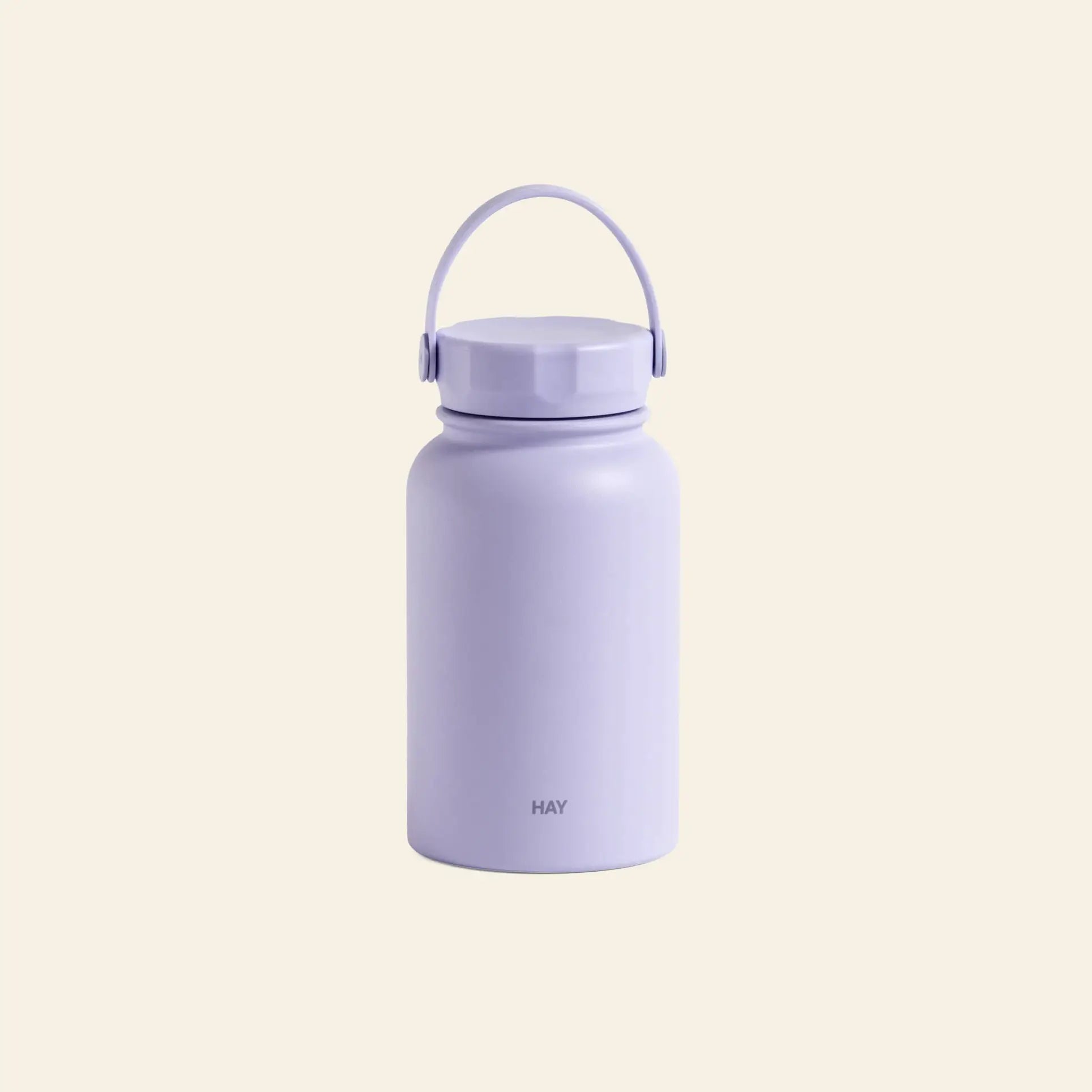 The HAY Mono Thermal Bottle by HAY is a stylish, minimalist light purple bottle with a handle and screw-on lid, featuring HAY near the base, ideal for beverages and shown against a plain beige background.