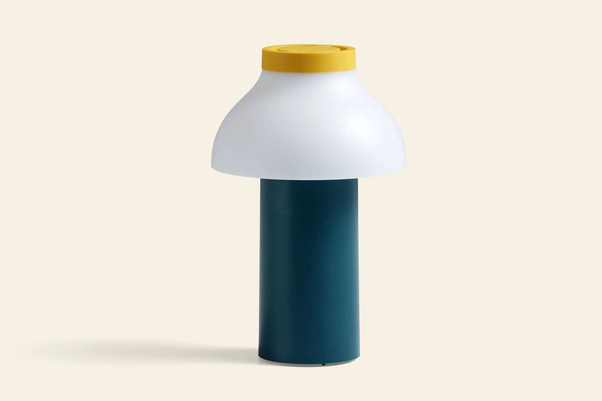 The HAY PC Portable Lamp by HAY features a modern Art Deco design with a cylindrical dark teal base, wide white dome-shaped shade, and yellow circular top—ideal as a portable desk lamp against light beige backgrounds.