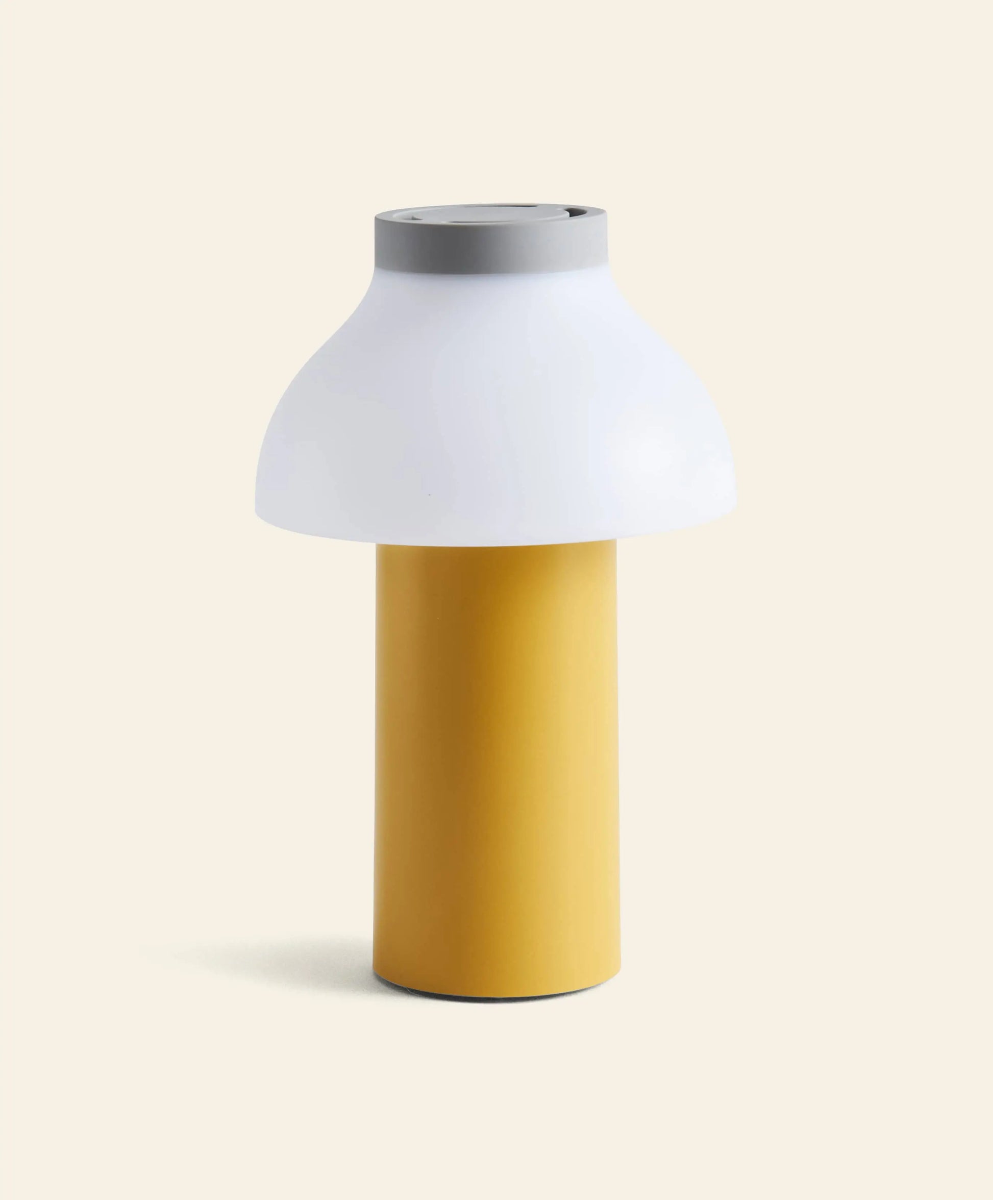 The HAY PC Portable Lamp by HAY features a modern cylindrical yellow base and a wide white dome-shaped shade, set against an off-white background, with subtle Art Deco design influences.