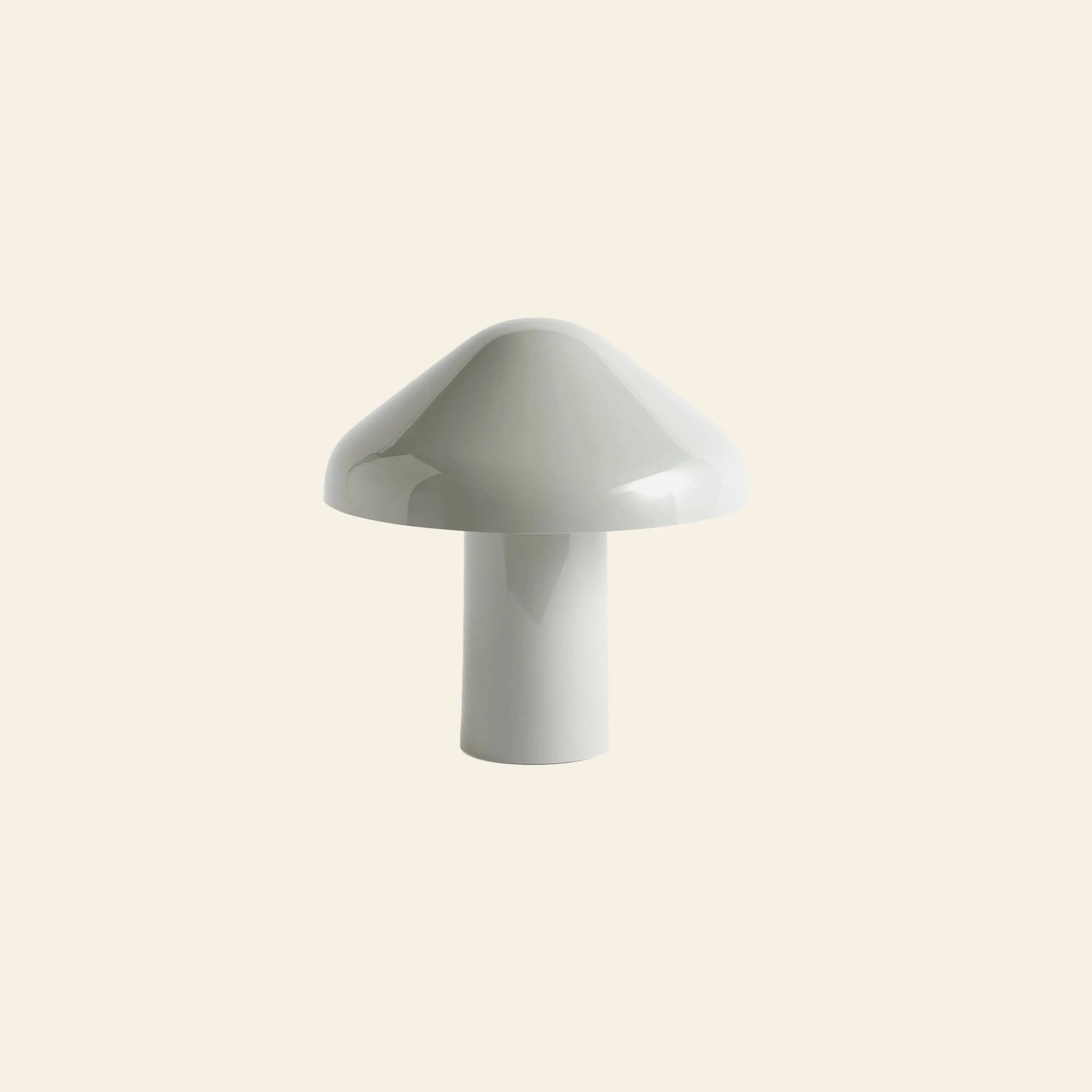 The HAY Pao Portable Lamp by HAY features a minimalistic white ceramic design with a mushroom-shaped rounded dome top and cylindrical base, inspired by Naoto Fukasawa, set against a plain beige background.