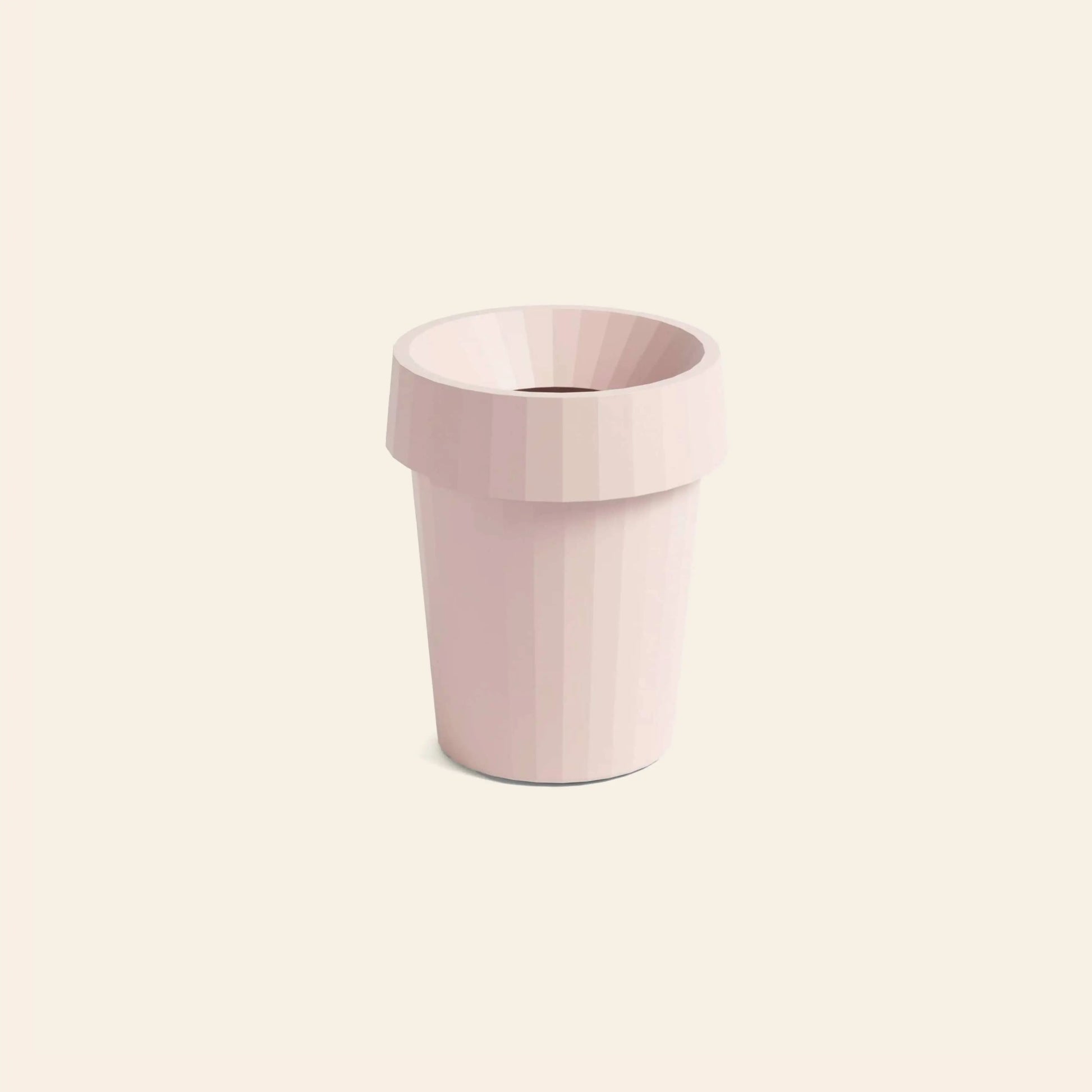 The HAY Shade Bin by HAY, a light pink faceted polypropylene flower pot with a wide rim and cylindrical shape, is centered on a plain, light cream background.