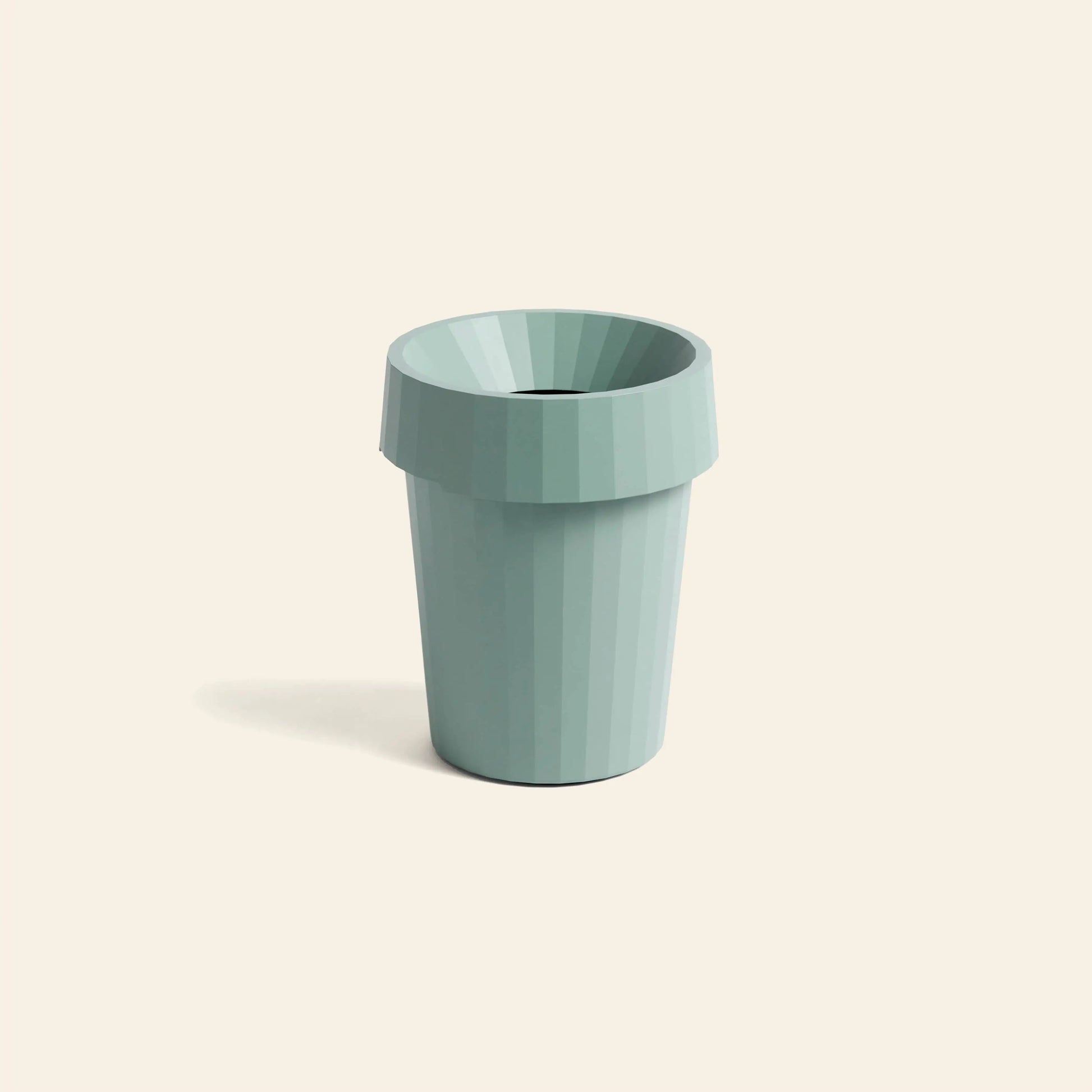 The HAY Shade Bin by HAY, crafted from durable light blue polypropylene with a faceted design and wide rim, sits on an off-white background, casting a soft shadow that highlights its subtle, elegant form.