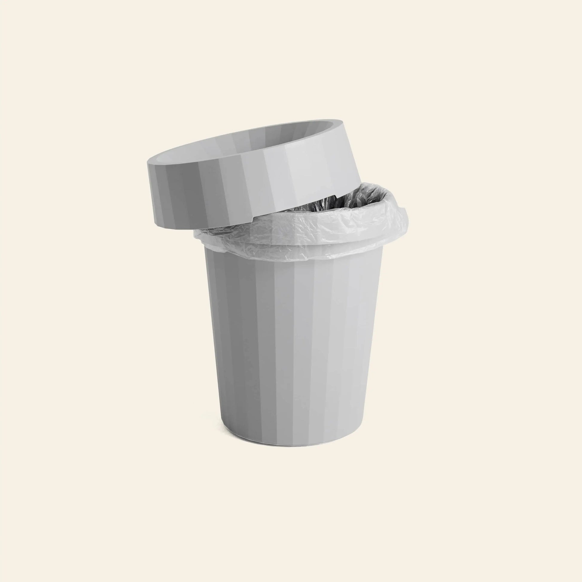 The HAY Shade Bin by HAY is a gray, ribbed polypropylene bin with a plastic liner and tilted lid, shown on a plain light background in muted tones.