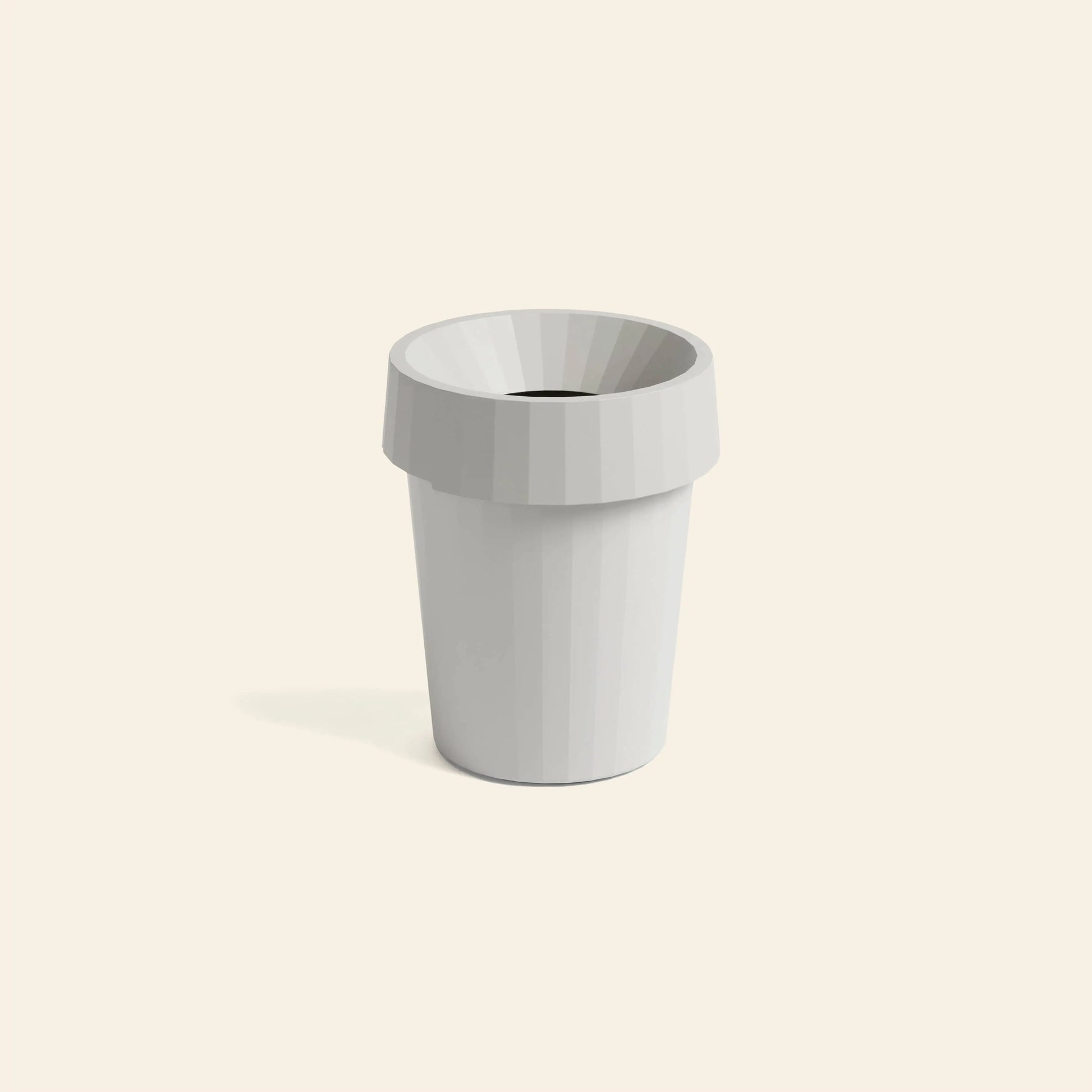 A minimalist, white HAY Shade Bin by HAY made of durable polypropylene with a wide rim is centered on a plain, light beige background in muted tones. The bin casts a soft shadow to its left.
