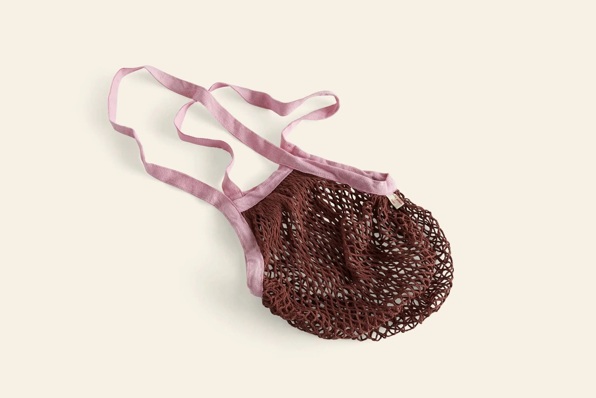 The HAY Sobremesa Market Net Bag by HAY is a reusable brown bag with light pink handles and trim, shown flat on a plain, light background—offering a stylish way to carry your groceries.