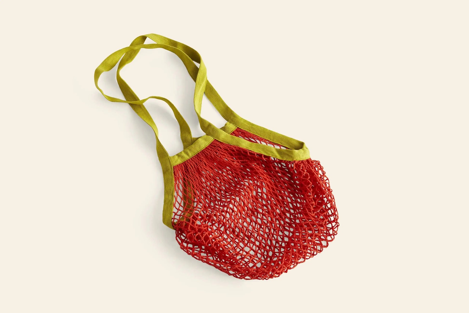 The HAY Sobremesa Market Net Bag by HAY, shown flat on a light beige background, features a reusable red design with green handles—a stylish way to carry groceries.